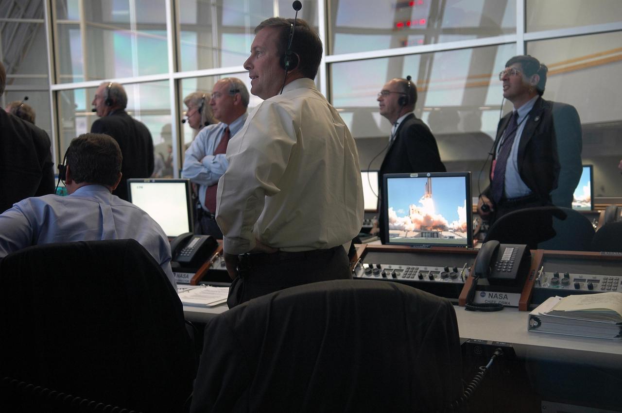KENNEDY SPACE CENTER, FLA. -    In Firing Room 4 of the Launch Control Center, the launch team stands to view the liftoff of Space Shuttle Discovery on mission STS-121 -- the first ever Independence Day launch of a space shuttle.  Liftoff was on-time at 2:38 p.m. EDT. During the 12-day mission, the STS-121 crew of seven will test new equipment and procedures to improve shuttle safety, as well as deliver supplies and make repairs to the International Space Station. Landing is scheduled for July 16 or 17 at Kennedy's Shuttle Landing Facility. Photo credit: NASA/Kim Shiflett