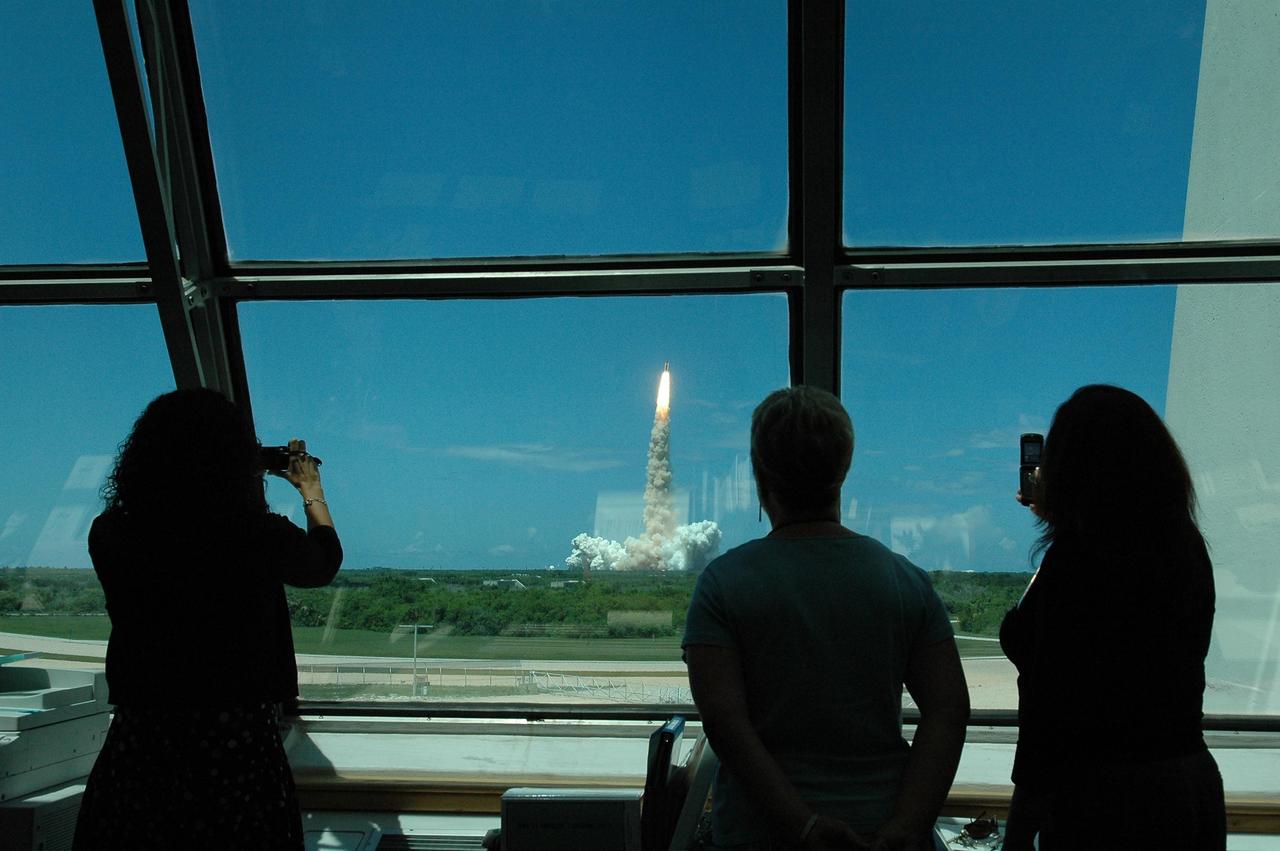 KENNEDY SPACE CENTER, FLA. -   Workers in Firing Room 4 of the Launch Control Center take advantage of the view as Space Shuttle Discovery lifts off on mission STS-121 -- the first ever Independence Day launch of a space shuttle.  Liftoff was on-time at 2:38 p.m. EDT.   During the 12-day mission, the STS-121 crew of seven will test new equipment and procedures to improve shuttle safety, as well as deliver supplies and make repairs to the International Space Station.  Landing is scheduled for July 16 or 17 at Kennedy's Shuttle Landing Facility.   Photo credit: NASA/Kim Shiflett