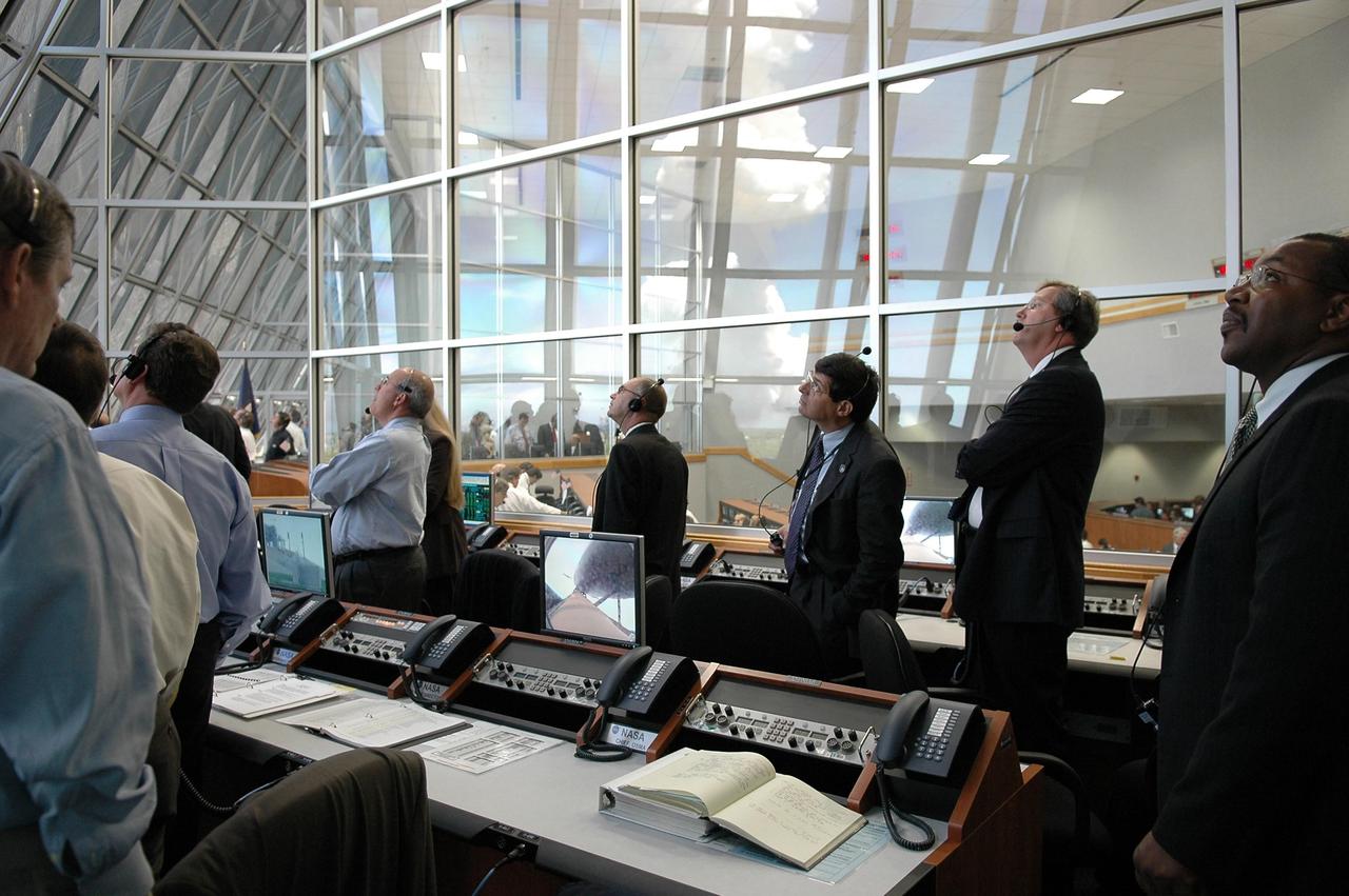 KENNEDY SPACE CENTER, FLA. -  Members of the launch team in Firing Room 4 of the Launch Control Center watch the historic ride of Space Shuttle Discovery as it rockets through the sky on mission STS-121 -- the first ever Independence Day launch of a space shuttle. Liftoff was on-time at 2:38 p.m. EDT.  During the 12-day mission, the STS-121 crew of seven will test new equipment and procedures to improve shuttle safety, as well as deliver supplies and make repairs to the International Space Station.  Landing is scheduled for July 16 or 17 at Kennedy's Shuttle Landing Facility.   Photo credit: NASA/Kim Shiflett