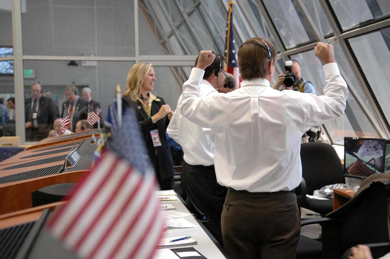 KENNEDY SPACE CENTER, FLA. -  In Firing Room 4 of the Launch Control Center, Shuttle Launch Director Mike Leinbach (foreground) cheers over the successful liftoff of Space Shuttle Discovery, watching it rocket through the sky on mission STS-121 -- the first ever Independence Day launch of a space shuttle.  At far left is Stephanie Stilson,  NASA flow director in the Process Integration Branch of the Shuttle Processing Directorate, who began conducting Discovery's processing operations in December 2000. Liftoff was on-time at 2:38 p.m. EDT.  During the 12-day mission, the STS-121 crew of seven will test new equipment and procedures to improve shuttle safety, as well as deliver supplies and make repairs to the International Space Station.  Landing is scheduled for July 16 or 17 at Kennedy's Shuttle Landing Facility.   Photo credit: NASA/Kim Shiflett
