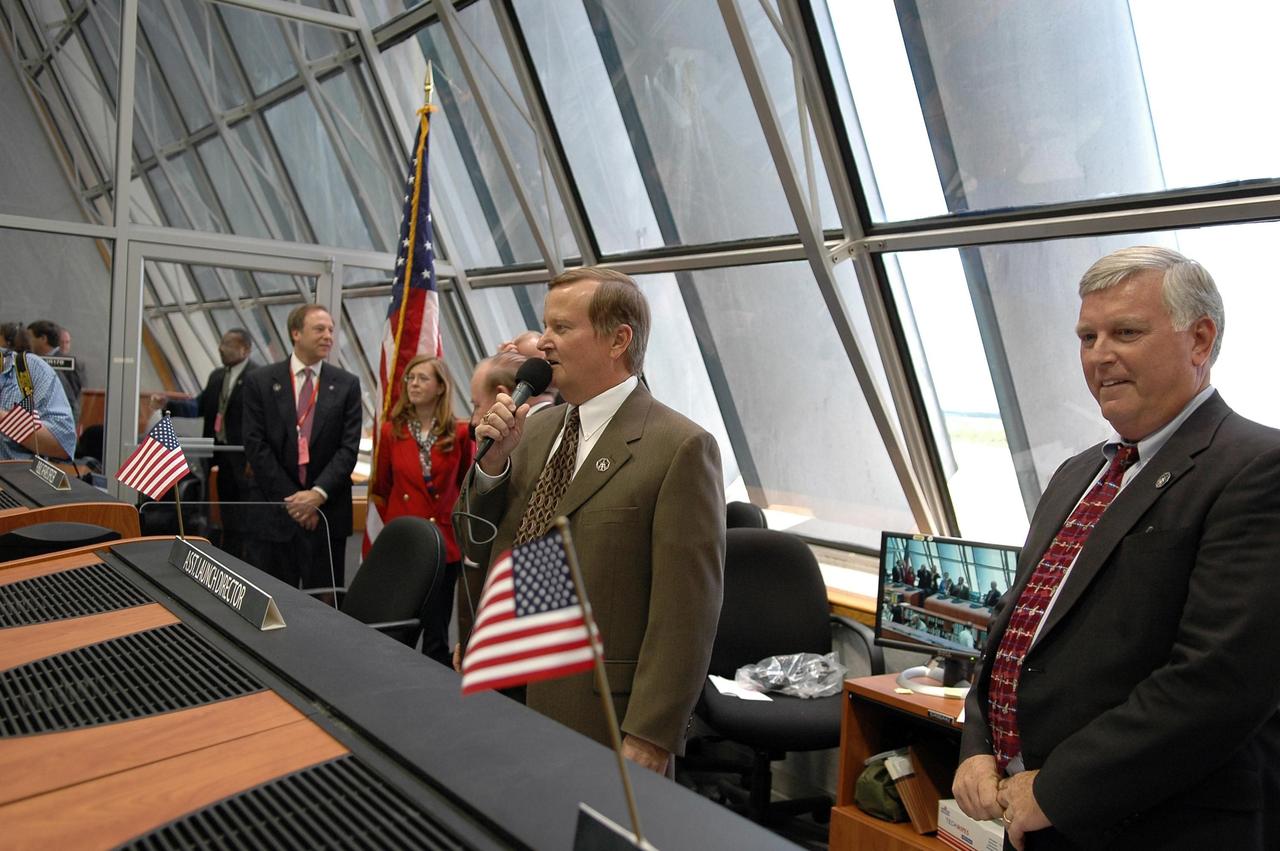 KENNEDY SPACE CENTER, FLA. -  In Firing Room 4 of the Launch Control Center, Shuttle Launch Director Mike Leinbach (center) congratulates the launch team after the successful launch of Space Shuttle Discovery on mission STS-121.  The launch was the first ever to take place on Independence Day.  At far right is Center Director Jim Kennedy.  During the 12-day mission, the STS-121 crew of seven will test new equipment and procedures to improve shuttle safety, as well as deliver supplies and make repairs to the International Space Station.  Landing is scheduled for July 16 or 17 at Kennedy's Shuttle Landing Facility.   Photo credit: NASA/Kim Shiflett