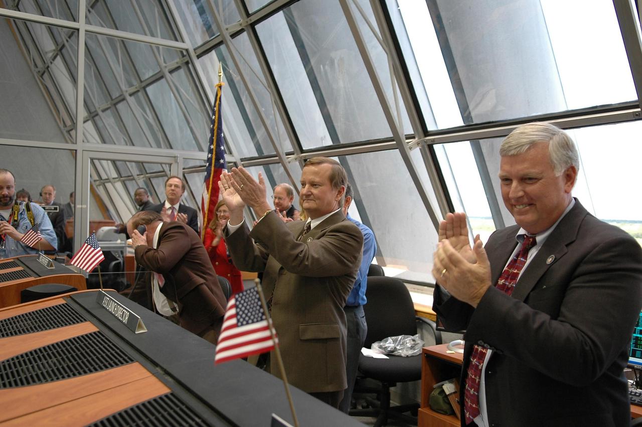 KENNEDY SPACE CENTER, FLA. -  In Firing Room 4 of the Launch Control Center, Shuttle Launch Director Mike Leinbach (center) and Center Director Jim Kennedy congratulate the launch team after the successful launch of Space Shuttle Discovery on mission STS-121.  The launch was the first ever to take place on Independence Day.    During the 12-day mission, the STS-121 crew of seven will test new equipment and procedures to improve shuttle safety, as well as deliver supplies and make repairs to the International Space Station.  Landing is scheduled for July 16 or 17 at Kennedy's Shuttle Landing Facility.   Photo credit: NASA/Kim Shiflett