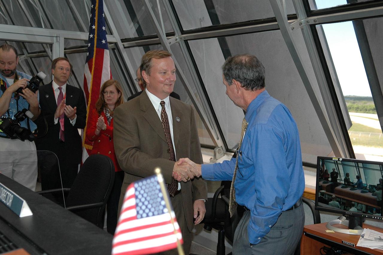 KENNEDY SPACE CENTER, FLA. -   In Firing Room 4 of the Launch Control Center, Shuttle Launch Director Mike Leinbach (center) is congratulated by NASA Administrator Mike Griffin (right) for the successful launch of Space Shuttle Discovery on mission STS-121.  The launch was the first ever to take place on Independence Day.  Behind Leinbach are David R. Mould,  assistant administrator for Public Affairs NASA, and Lisa Malone, director of External Relations at Kennedy. Liftoff was on-time at 2:38 p.m. EDT.   During the 12-day mission, the STS-121 crew of seven will test new equipment and procedures to improve shuttle safety, as well as deliver supplies and make repairs to the International Space Station.  Landing is scheduled for July 16 or 17 at Kennedy's Shuttle Landing Facility.   Photo credit: NASA/Kim Shiflett