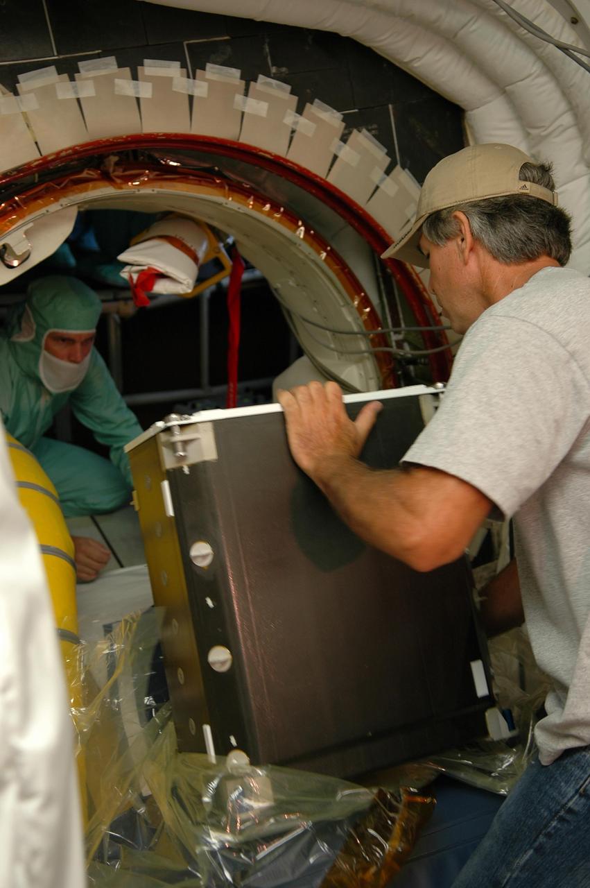 KENNEDY SPACE CENTER, FLA. -   In the White Room on Launch Pad 39B, a worker hands off a food container to someone inside Space Shuttle Discovery to store it for mission STS-121.  The White Room, which extends from the fixed service structure, provides access into the orbiter on the pad.  Astronauts are supplied with three balanced meals, plus snacks.  Foods flown on space missions are researched and developed at the Space Food Systems Laboratory at the Johnson Space Center (JSC) in Houston, which is staffed by food scientists, dietitians and engineers.   Each astronaut’s food stored aboard the space shuttle is identified by a colored dot affixed to each package.  Launch of Space Shuttle Discovery on mission STS-121 is scheduled for July 1. Photo credit: NASA/Kim Shiflett