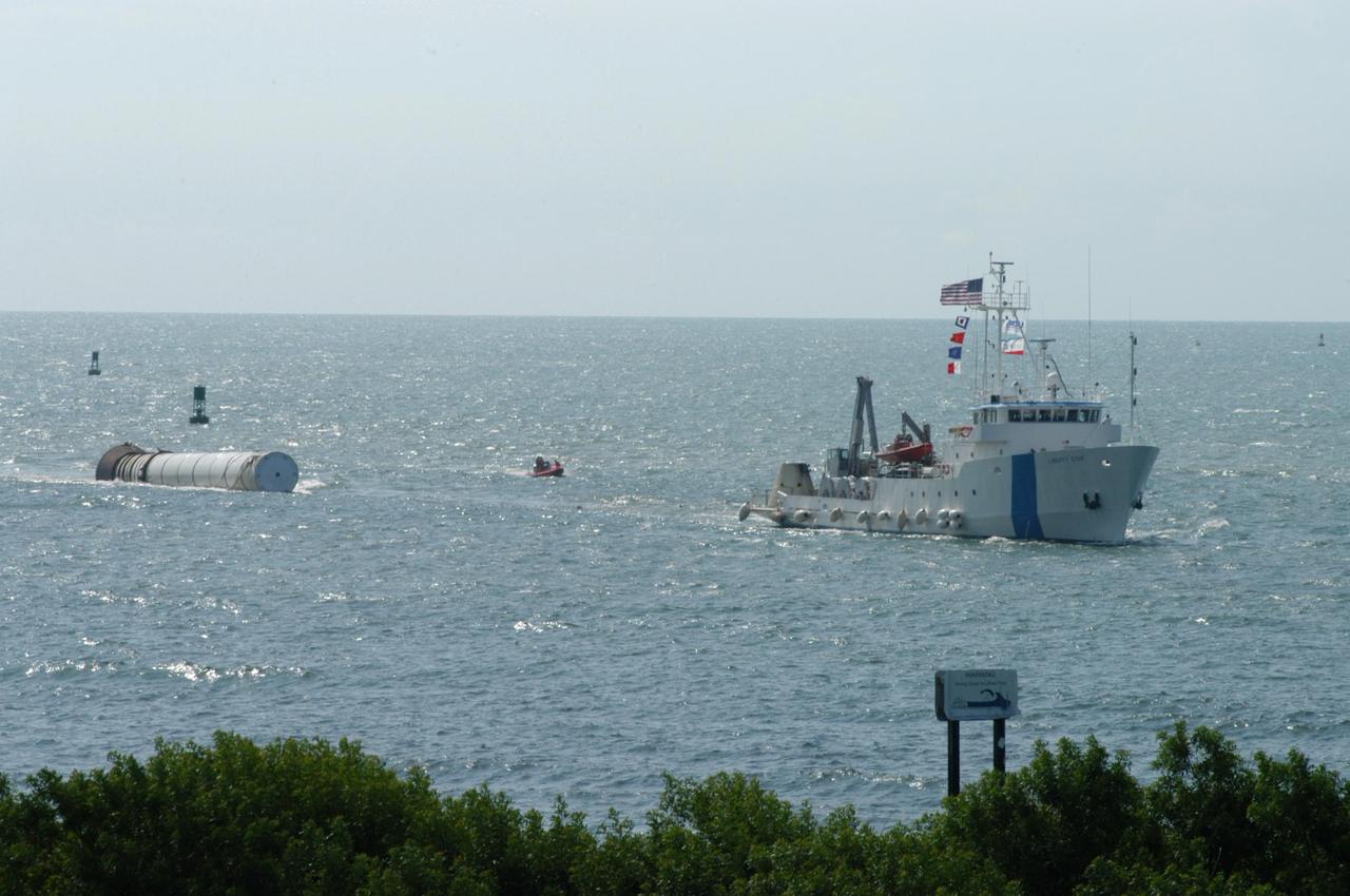 KENNEDY SPACE CENTER, FLA. - The SRB Retrieval Ship Liberty Star tows a spent solid rocket booster back to Port Canaveral. The booster is from Space Shuttle Discovery, which launched on July 4. The space shuttle’s solid rocket booster casings and associated flight hardware are recovered at sea. The boosters impact the Atlantic Ocean approximately seven minutes after liftoff. The splashdown area is a square of about 6 by 9 nautical miles located about 140 nautical miles downrange from the launch pad. The retrieval ships are stationed approximately 8 to 10 nautical miles from the impact area at the time of splashdown. As soon as the boosters enter the water, the ships accelerate to a speed of 15 knots and quickly close on the boosters. The pilot chutes and main parachutes are the first items to be brought on board. With the chutes and frustum recovered, attention turns to the boosters. The ship’s tow line is connected and the booster is returned to the Port and ,after transfer to a position alongside the ship, to Hangar AF at Cape Canaveral Air Force Station. There, the expended boosters are disassembled, refurbished and reloaded with solid propellant for reuse. Photo credit: NASA/George Shelton