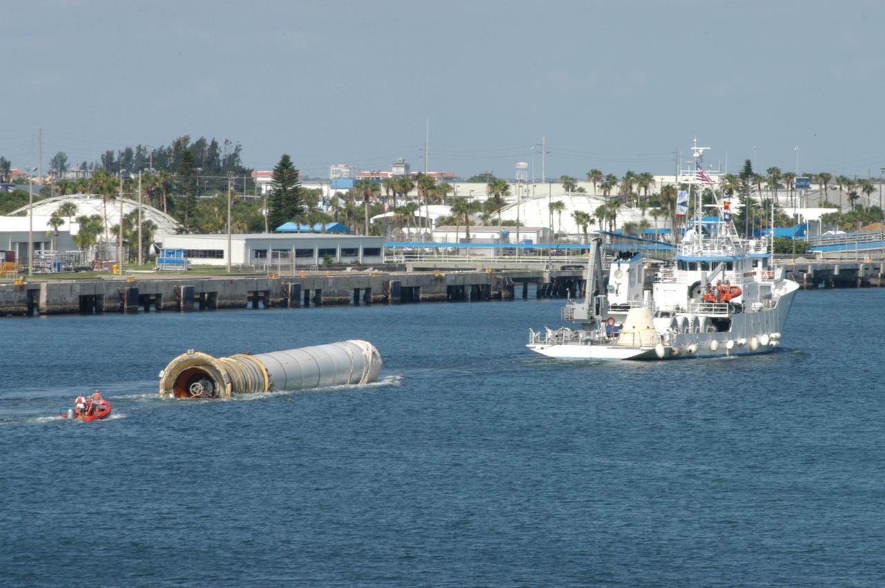 KENNEDY SPACE CENTER, FLA. - The SRB Retrieval Ship Liberty Star tows a spent solid rocket booster toward Port Canaveral. The booster is from Space Shuttle Discovery, which launched on July 4. The space shuttle’s solid rocket booster casings and associated flight hardware are recovered at sea. The boosters impact the Atlantic Ocean approximately seven minutes after liftoff. The splashdown area is a square of about 6 by 9 nautical miles located about 140 nautical miles downrange from the launch pad. The retrieval ships are stationed approximately 8 to 10 nautical miles from the impact area at the time of splashdown. As soon as the boosters enter the water, the ships accelerate to a speed of 15 knots and quickly close on the boosters. The pilot chutes and main parachutes are the first items to be brought on board. With the chutes and frustum recovered, attention turns to the boosters. The ship’s tow line is connected and the booster is returned to the Port and ,after transfer to a position alongside the ship, to Hangar AF at Cape Canaveral Air Force Station. There, the expended boosters are disassembled, refurbished and reloaded with solid propellant for reuse. Photo credit: NASA/George Shelton