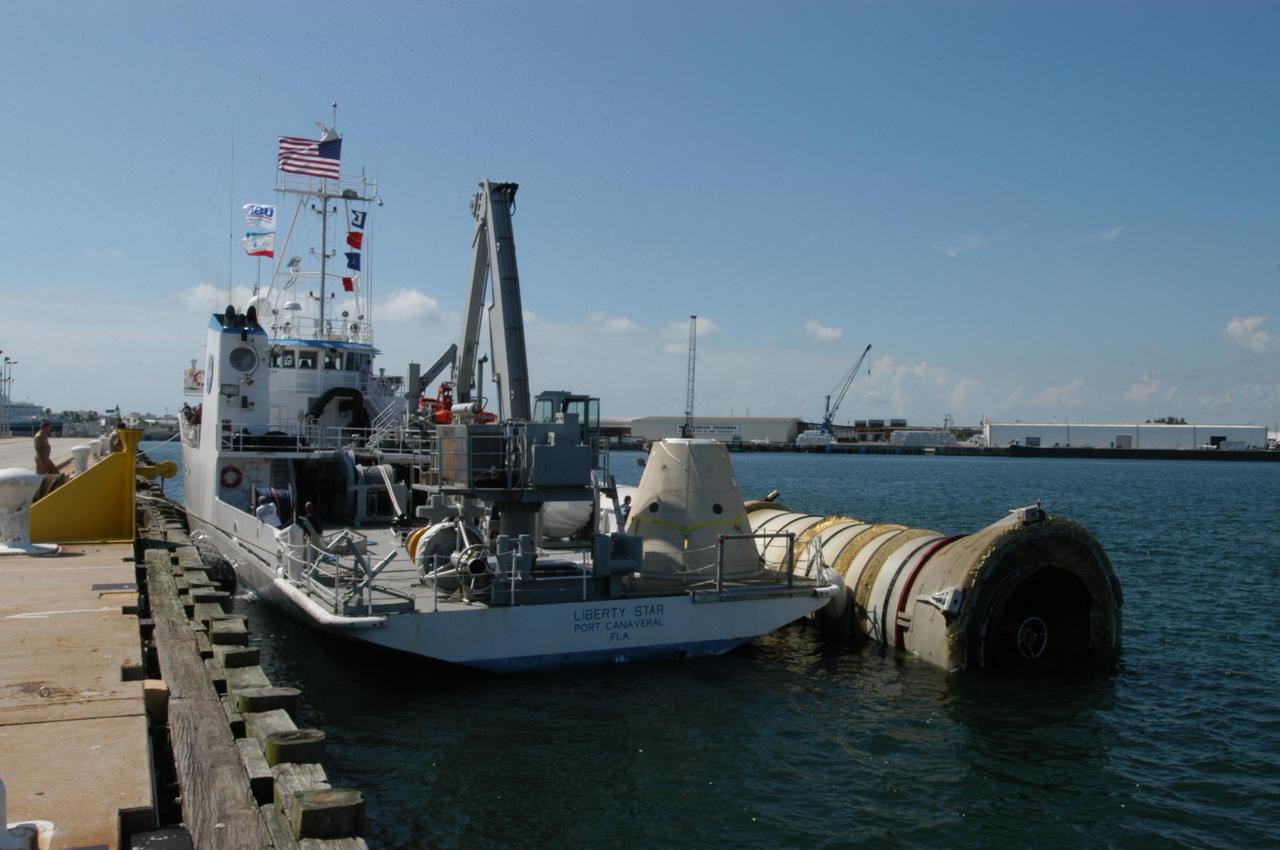 KENNEDY SPACE CENTER, FLA. - At a dock in Port Canaveral, the SRB Retrieval Ship Liberty Star has successfully transferred its tow cargo, a spent solid rocket booster, to a starboard position for the balance of its journey to Cape Canaveral Air Force Station. The booster is from Space Shuttle Discovery, which launched on July 4. The space shuttle’s solid rocket booster casings and associated flight hardware are recovered at sea. The boosters impact the Atlantic Ocean approximately seven minutes after liftoff. The splashdown area is a square of about 6 by 9 nautical miles located about 140 nautical miles downrange from the launch pad. The retrieval ships are stationed approximately 8 to 10 nautical miles from the impact area at the time of splashdown. As soon as the boosters enter the water, the ships accelerate to a speed of 15 knots and quickly close on the boosters. The pilot chutes and main parachutes are the first items to be brought on board. With the chutes and frustum recovered, attention turns to the boosters. The ship’s tow line is connected and the booster is returned to the Port and ,after transfer to a position alongside the ship, to Hangar AF at Cape Canaveral Air Force Station. There, the expended boosters are disassembled, refurbished and reloaded with solid propellant for reuse. Photo credit: NASA/George Shelton
