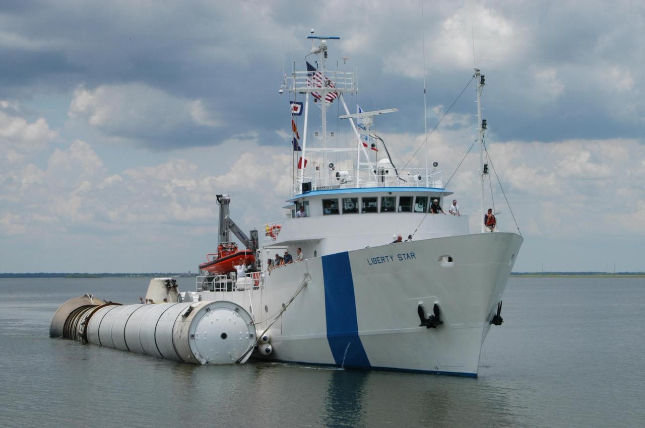 KENNEDY SPACE CENTER, FLA. -   The SRB Retrieval Ship Liberty Star closes in on the dock at Hangar AF, Cape Canaveral Air Force Station, with a spent solid rocket booster alongside.  The booster is from Space Shuttle Discovery, which launched on July 4.  The space shuttle’s solid rocket booster casings and associated flight hardware are recovered at sea.  The boosters impact the Atlantic Ocean approximately seven minutes after liftoff. The splashdown area is a square of about 6 by 9 nautical miles located about 140 nautical miles downrange from the launch pad. The retrieval ships are stationed approximately 8 to 10 nautical miles from the impact area at the time of splashdown. As soon as the boosters enter the water, the ships accelerate to a speed of 15 knots and quickly close on the boosters.  The pilot chutes and main parachutes are the first items to be brought on board. With the chutes and frustum recovered, attention turns to the boosters. The ship’s tow line is connected and the booster is returned to the Port and ,after transfer to a position alongside the ship, to Hangar AF at Cape Canaveral Air Force Station.  There, the expended boosters are disassembled, refurbished and reloaded with solid propellant for reuse.  Photo credit: NASA/George Shelton