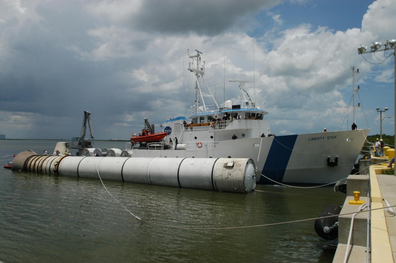 KENNEDY SPACE CENTER, FLA. -   At the dock at Hangar AF, Cape Canaveral Air Force Station, the SRB Retrieval Ship Liberty Star gets ready to transfer the spent solid rocket booster to a straddle crane that will lift it out of the water.  The booster is from Space Shuttle Discovery, which launched on July 4.  The space shuttle’s solid rocket booster casings and associated flight hardware are recovered at sea.  The boosters impact the Atlantic Ocean approximately seven minutes after liftoff. The splashdown area is a square of about 6 by 9 nautical miles located about 140 nautical miles downrange from the launch pad. The retrieval ships are stationed approximately 8 to 10 nautical miles from the impact area at the time of splashdown. As soon as the boosters enter the water, the ships accelerate to a speed of 15 knots and quickly close on the boosters.  The pilot chutes and main parachutes are the first items to be brought on board. With the chutes and frustum recovered, attention turns to the boosters. The ship’s tow line is connected and the booster is returned to the Port and ,after transfer to a position alongside the ship, to Hangar AF at Cape Canaveral Air Force Station.  There, the expended boosters are disassembled, refurbished and reloaded with solid propellant for reuse.  Photo credit: NASA/George Shelton