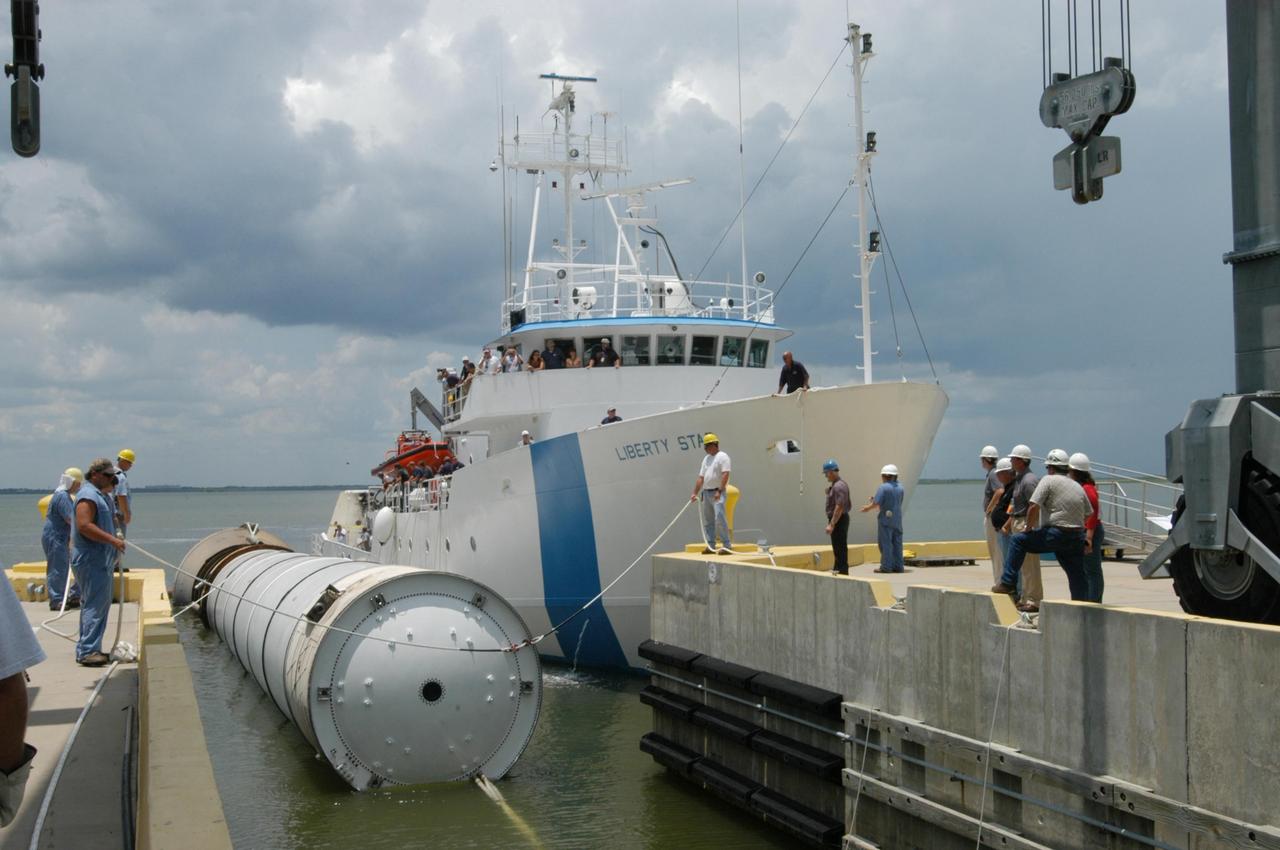 KENNEDY SPACE CENTER, FLA. - At the dock at Hangar AF, Cape Canaveral Air Force Station, workers move the spent solid rocket booster away from the SRB Retrieval Ship Liberty Star to an area beneath the straddle crane that will lift it out of the water. The booster is from Space Shuttle Discovery, which launched on July 4. The space shuttle’s solid rocket booster casings and associated flight hardware are recovered at sea. The boosters impact the Atlantic Ocean approximately seven minutes after liftoff. The splashdown area is a square of about 6 by 9 nautical miles located about 140 nautical miles downrange from the launch pad. The retrieval ships are stationed approximately 8 to 10 nautical miles from the impact area at the time of splashdown. As soon as the boosters enter the water, the ships accelerate to a speed of 15 knots and quickly close on the boosters. The pilot chutes and main parachutes are the first items to be brought on board. With the chutes and frustum recovered, attention turns to the boosters. The ship’s tow line is connected and the booster is returned to the Port and ,after transfer to a position alongside the ship, to Hangar AF at Cape Canaveral Air Force Station. There, the expended boosters are disassembled, refurbished and reloaded with solid propellant for reuse. Photo credit: NASA/George Shelton