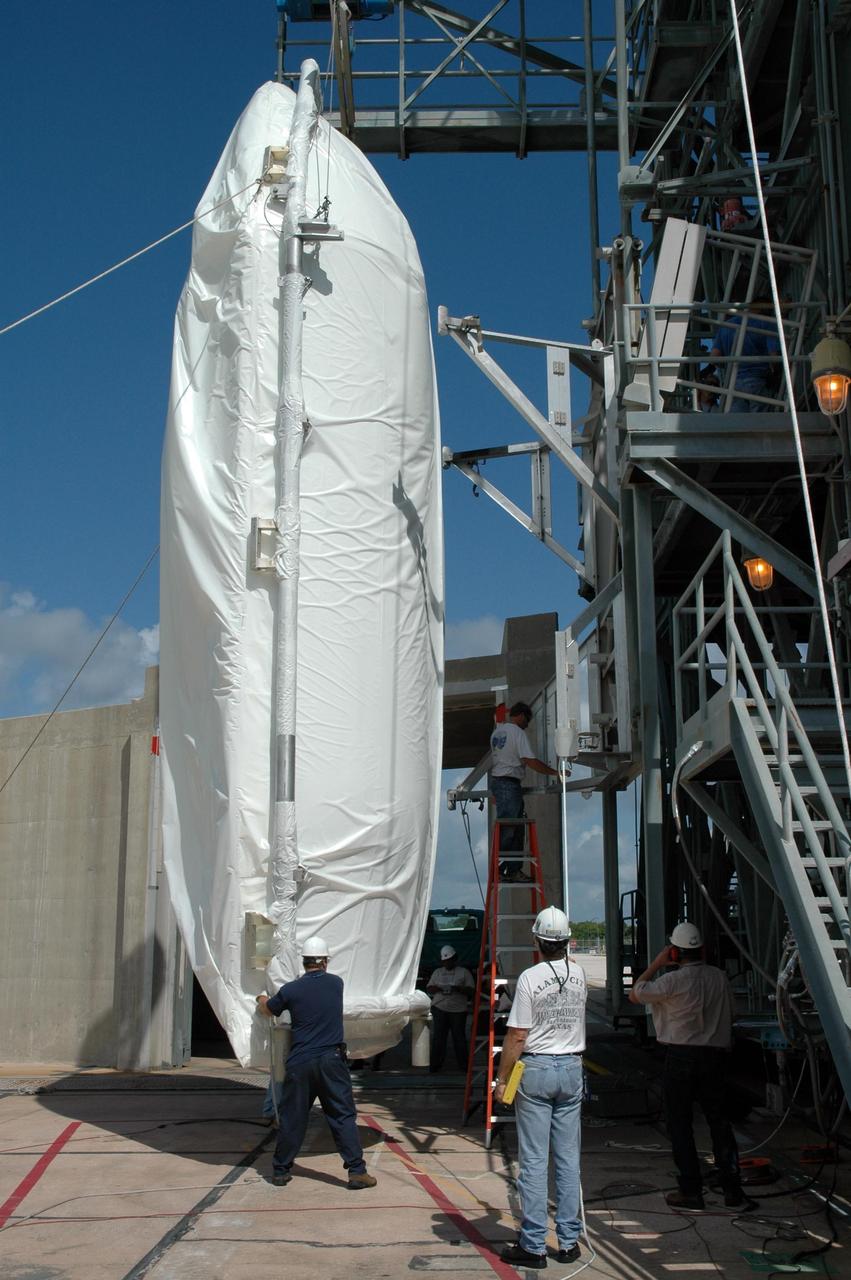 KENNEDY SPACE CENTER, FLA. - Shrouded with a protective cover, half of the payload fairing for the STEREO spacecraft has been raised to a vertical position in front of the mobile service tower on Launch Pad 17-B at Cape Canaveral Air Force Station in Florida. The fairing will be lifted into the clean room in the tower and later installed around the spacecraft for protection during launch. The fairing is a molded structure that fits flush with the outside surface of the Delta II upper stage booster and forms an aerodynamically smooth nose cone, protecting the spacecraft during launch and ascent. STEREO, which stands for Solar Terrestrial Relations Observatory, comprises two spacecraft. The STEREO mission is the first to take measurements of the sun and solar wind in 3-dimension. This new view will improve our understanding of space weather and its impact on the Earth. STEREO is expected to lift off aboard a Boeing Delta II rocket in August 2006. Photo credit: NASA/Jim Grossmann