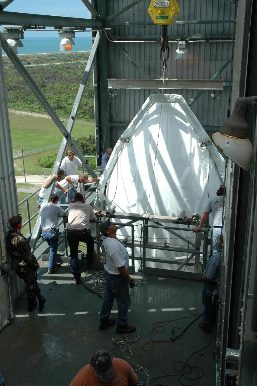KENNEDY SPACE CENTER, FLA. - Inside the mobile service tower on Launch Pad 17-B at Cape Canaveral Air Force Station in Florida, the shrouded first half of the payload fairing for the STEREO spacecraft is lowered into a clean room. It will later be installed around the spacecraft for protection during launch. The fairing will be moved into the clean room in the tower and later installed around the spacecraft for protection during launch. The fairing is a molded structure that fits flush with the outside surface of the Delta II upper stage booster and forms an aerodynamically smooth nose cone, protecting the spacecraft during launch and ascent. STEREO, which stands for Solar Terrestrial Relations Observatory, comprises two spacecraft. The STEREO mission is the first to take measurements of the sun and solar wind in 3-dimension. This new view will improve our understanding of space weather and its impact on the Earth. STEREO is expected to lift off aboard a Boeing Delta II rocket in August 2006. Photo credit: NASA/Jim Grossmann