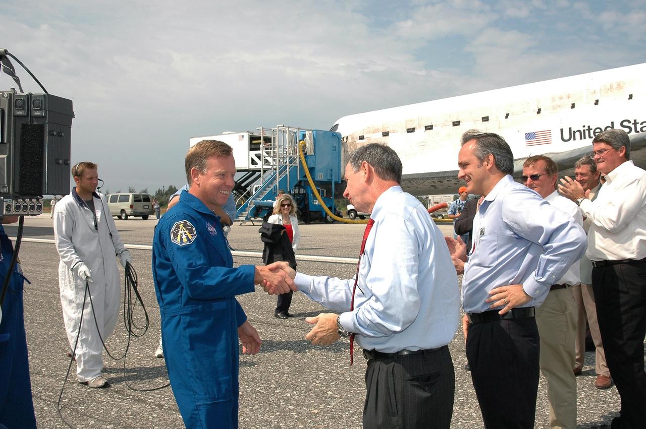 KENNEDY SPACE CENTER, FLA. - STS-121 Mission Commander Steven Lindsey is greeted by NASA Administrator Mike Griffin, Associate Administrator Rex Geveden, Shuttle Launch Director Mike Leinbach, KSC Deputy Director Bill Parsons and other senior managers after leaving the orbiter Discovery, in the background. The rest of the crew are Pilot Mark Kelly and Mission Specialists Piers Sellers, Lisa Nowak and Stephanie Wilson. Mission Specialist Thomas Reiter, who launched with the crew on July 4, remained on the station to join the Expedition 13 crew there. Discovery's smooth and perfect landing was on time at 9:14 a.m. EDT on Runway 15 of NASA's Shuttle Landing Facility after traveling 5.3 million miles on 202 orbits. Mission elapsed time was 12 days, 18 hours, 37 minutes and 54 seconds. The landing is the 62nd at Kennedy Space Center and the 32nd for Discovery. Photo credit: NASA/Kim Shiflett