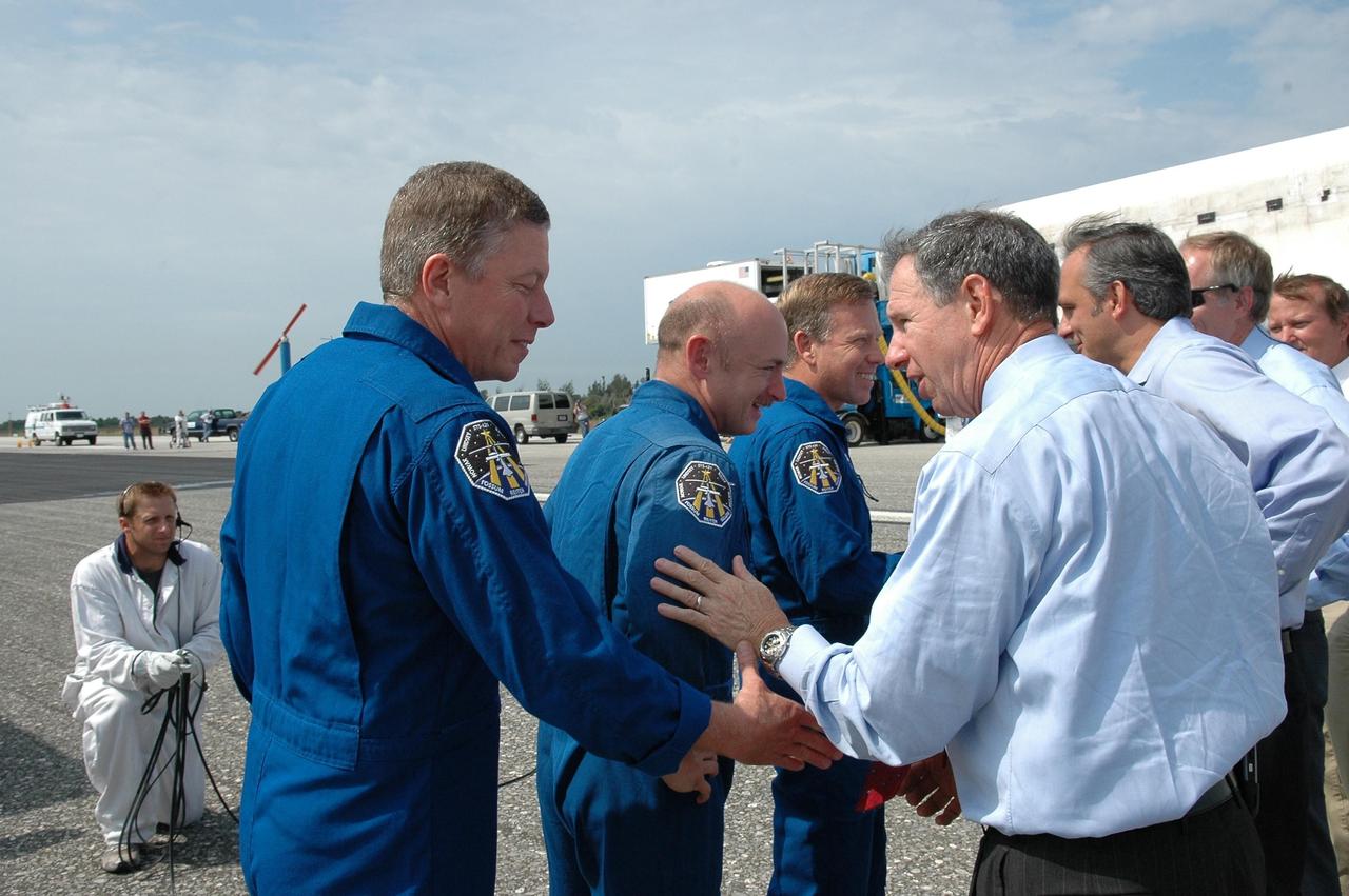 KENNEDY SPACE CENTER, FLA. - (From left) STS-121 Mission Specialist Michael Fossum, Pilot Mark Kelly and Commander Steven Lindsey are greeted by NASA Administrator Mike Griffin (foreground, right), Associate Administrator Rex Geveden and other senior managers after leaving the orbiter Discovery, in the background. The rest of the crew are Mission Specialists Piers Sellers, Lisa Nowak and Stephanie Wilson. Mission Specialist Thomas Reiter, who launched with the crew on July 4, remained on the station to join the Expedition 13 crew there. Discovery's smooth and perfect landing was on time at 9:14 a.m. EDT on Runway 15 of NASA's Shuttle Landing Facility after traveling 5.3 million miles on 202 orbits. Mission elapsed time was 12 days, 18 hours, 37 minutes and 54 seconds. The landing is the 62nd at Kennedy Space Center and the 32nd for Discovery. Photo credit: NASA/Kim Shiflett