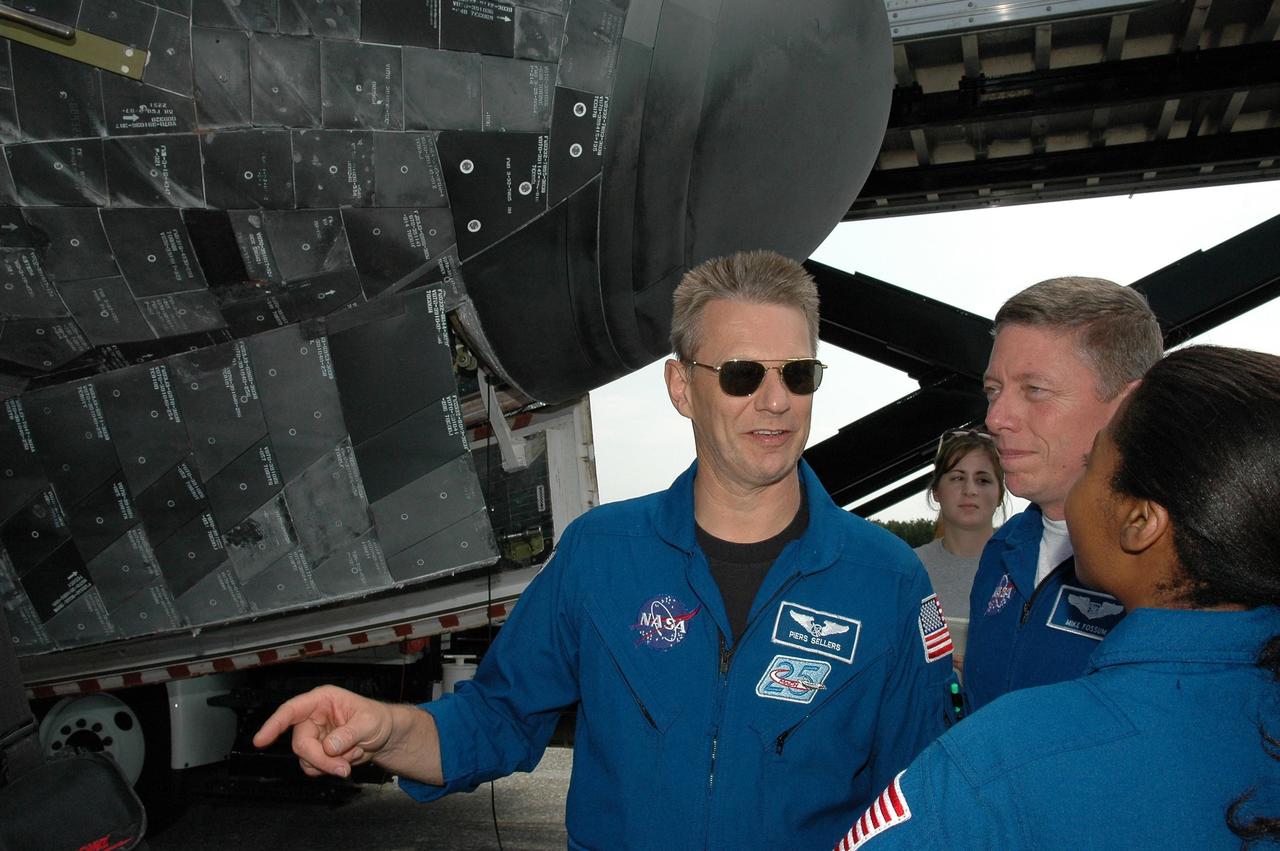 KENNEDY SPACE CENTER, FLA. -   During the traditional post-flight walk-around after the landing of an orbiter, Mission Specialists Piers Sellers, Michael Fossum and Stephanie Wilson get a close look at the nose cone, behind them.   Discovery's smooth and perfect landing was on time at 9:14 a.m. EDT on Runway 15 of NASA's Shuttle Landing Facility after traveling 5.3 million miles on 202 orbits. Mission elapsed time was 12 days, 18 hours, 37 minutes and 54 seconds.  The landing is the 62nd at Kennedy Space Center and the 32nd for Discovery. Photo credit: NASA/Kim Shiflett