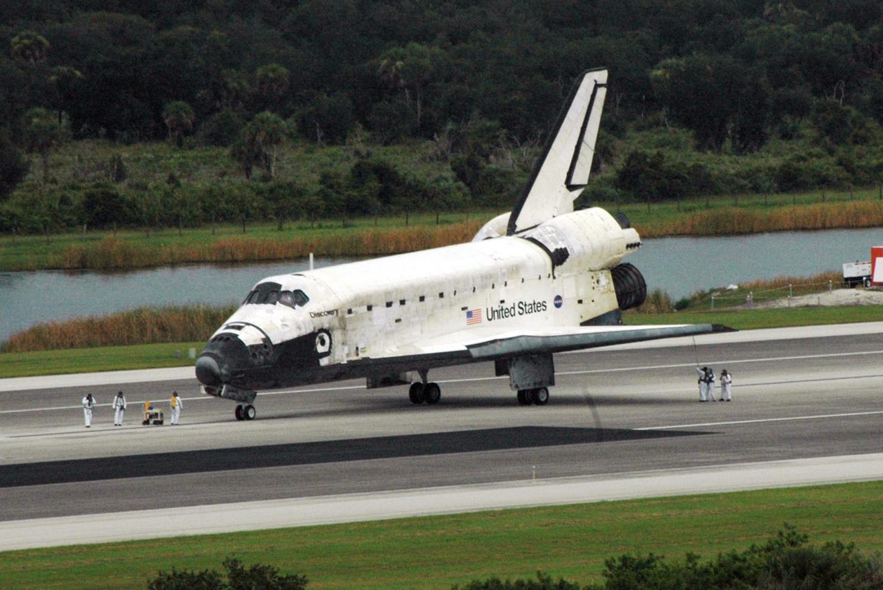 KENNEDY SPACE CENTER, FLA. - After Discovery's safe landing on Runway 15 at NASA's Shuttle Landing Facility, safety assessment teams dressed in protective attire and with breathing apparatus obtain vapor level readings around the orbiter and test for possible explosive or toxic gases such as hydrogen, hydrazine, monomethyl-hydrazine, nitrogen tetroxide or ammonia . Completing mission STS-121 to the International Space Station, Discovery traveled 5.3 million miles, landing on orbit 202. Mission elapsed time was 12 days, 18 hours, 37 minutes and 54 seconds. Main gear touchdown occurred on time at 9:14:43 EDT. Wheel stop was at 9:15:49 EDT. The returning crew members are Commander Steven Lindsey, Pilot Mark Kelly and Mission Specialists Piers Sellers, Michael Fossum, Lisa Nowak and Stephanie Wilson. Mission Specialist Thomas Reiter, who launched with the crew on July 4, remained on the station to join the Expedition 13 crew there. The landing is the 62nd at Kennedy Space Center and the 32nd for Discovery. Discovery's landing was as exhilarating as its launch, the first to take place on America's Independence Day. During the mission, the STS-121 crew tested new equipment and procedures to improve shuttle safety, and delivered supplies and made repairs to the International Space Station. Photo credit: NASA/Ken Thornsley