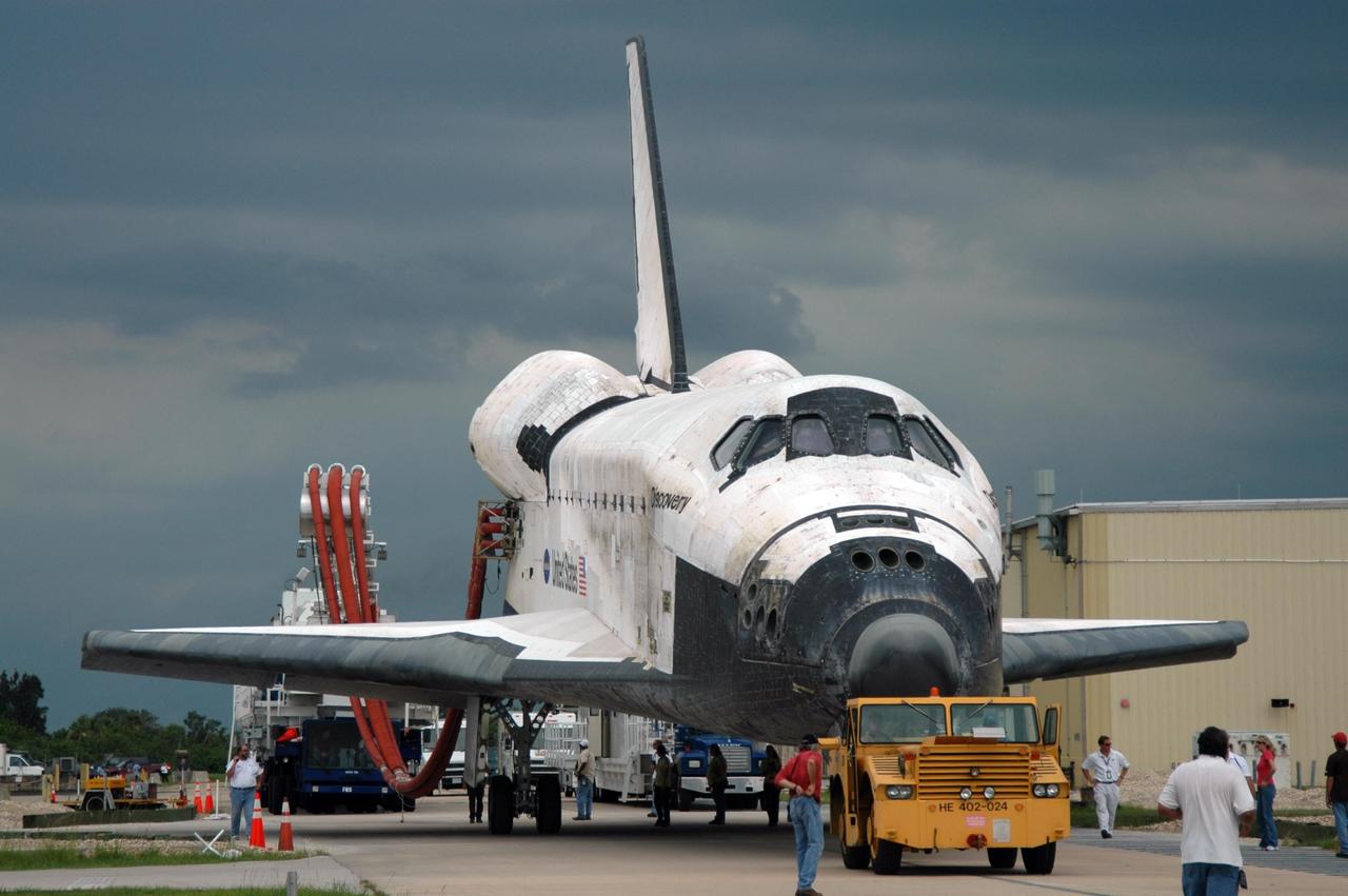 KENNEDY SPACE CENTER, FLA. -    Under tow by a diesel-powered tractor, the orbiter Discovery rolls to the Orbiter Processing Facility from NASA's Shuttle Landing Facility on a two-mile tow-way. Umbilical lines for coolant and purge air are still attached.  Discovery landed at the SLF at 9:14 a.m. EDT, completing mission STS-121. Discovery traveled  5.3 million miles, landing on orbit 202.  Mission elapsed time was 12 days, 18 hours, 37 minutes and 54 seconds.  Main gear touchdown occurred on time at 9:14:43 EDT.  Wheel stop was at 9:15:49 EDT. During the mission, the STS-121 crew tested new equipment and procedures to improve shuttle safety, and delivered supplies and made repairs to the International Space Station.  Photo credit: NASA/Jim Grossmann