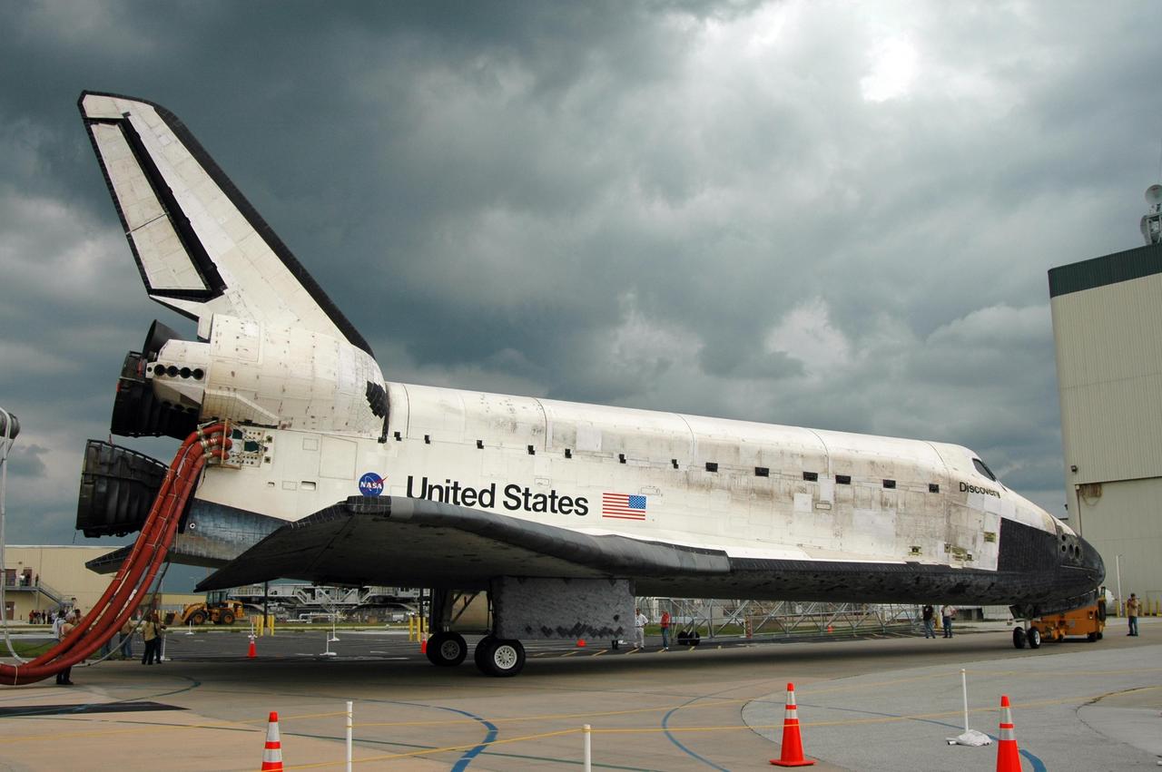 KENNEDY SPACE CENTER, FLA. -   Under tow by a diesel-powered tractor, the orbiter Discovery turns toward the Orbiter Processing Facility.  Umbilical lines for coolant and purge air are still attached.  Discovery landed at the SLF at 9:14 a.m. EDT, completing mission STS-121.  Discovery traveled  5.3 million miles, landing on orbit 202.  Mission elapsed time was 12 days, 18 hours, 37 minutes and 54 seconds.  Main gear touchdown occurred on time at 9:14:43 EDT.  Wheel stop was at 9:15:49 EDT. During the mission, the STS-121 crew tested new equipment and procedures to improve shuttle safety, and delivered supplies and made repairs to the International Space Station.  Photo credit: NASA/Jim Grossmann