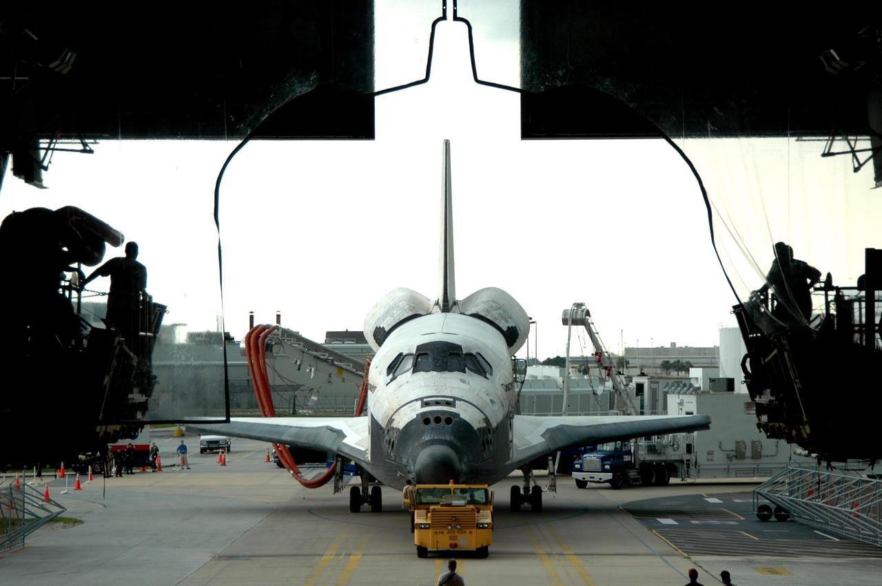 KENNEDY SPACE CENTER, FLA. -   Still being towed by a diesel-powered tractor, the orbiter Discovery is moved into the Orbiter Processing Facility.  Umbilical lines for coolant and purge air are still attached.  Discovery landed at the SLF at 9:14 a.m. EDT, completing mission STS-121. Discovery traveled  5.3 million miles, landing on orbit 202.  Mission elapsed time was 12 days, 18 hours, 37 minutes and 54 seconds.  Main gear touchdown occurred on time at 9:14:43 EDT.  Wheel stop was at 9:15:49 EDT. During the mission, the STS-121 crew tested new equipment and procedures to improve shuttle safety, and delivered supplies and made repairs to the International Space Station.  Photo credit: NASA/Jim Grossmann