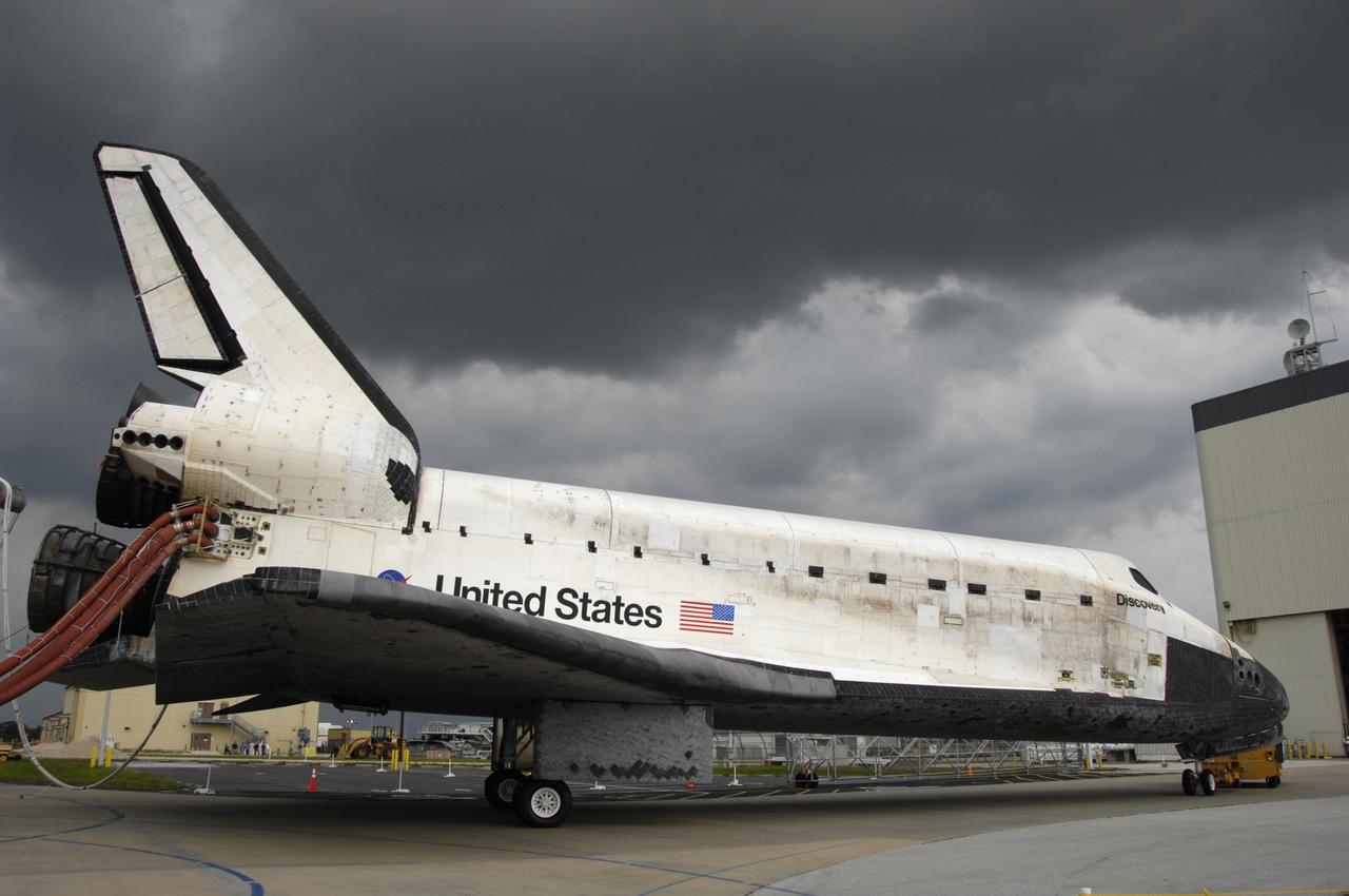 KENNEDY SPACE CENTER, FLA. -   As black clouds gather overhead, the orbiter Discovery arrives at the Orbiter Processing Facility after a two-mile tow from NASA's Shuttle Landing Facility. Umbilical lines for coolant and purge air are still attached.  Discovery landed at the SLF at 9:14 a.m. EDT, completing mission STS-121.  Discovery traveled  5.3 million miles, landing on orbit 202.  Mission elapsed time was 12 days, 18 hours, 37 minutes and 54 seconds.  Main gear touchdown occurred on time at 9:14:43 EDT.  Wheel stop was at 9:15:49 EDT. During the mission, the STS-121 crew tested new equipment and procedures to improve shuttle safety, and delivered supplies and made repairs to the International Space Station.  Photo courtesy of Nikon/Scott Andrews