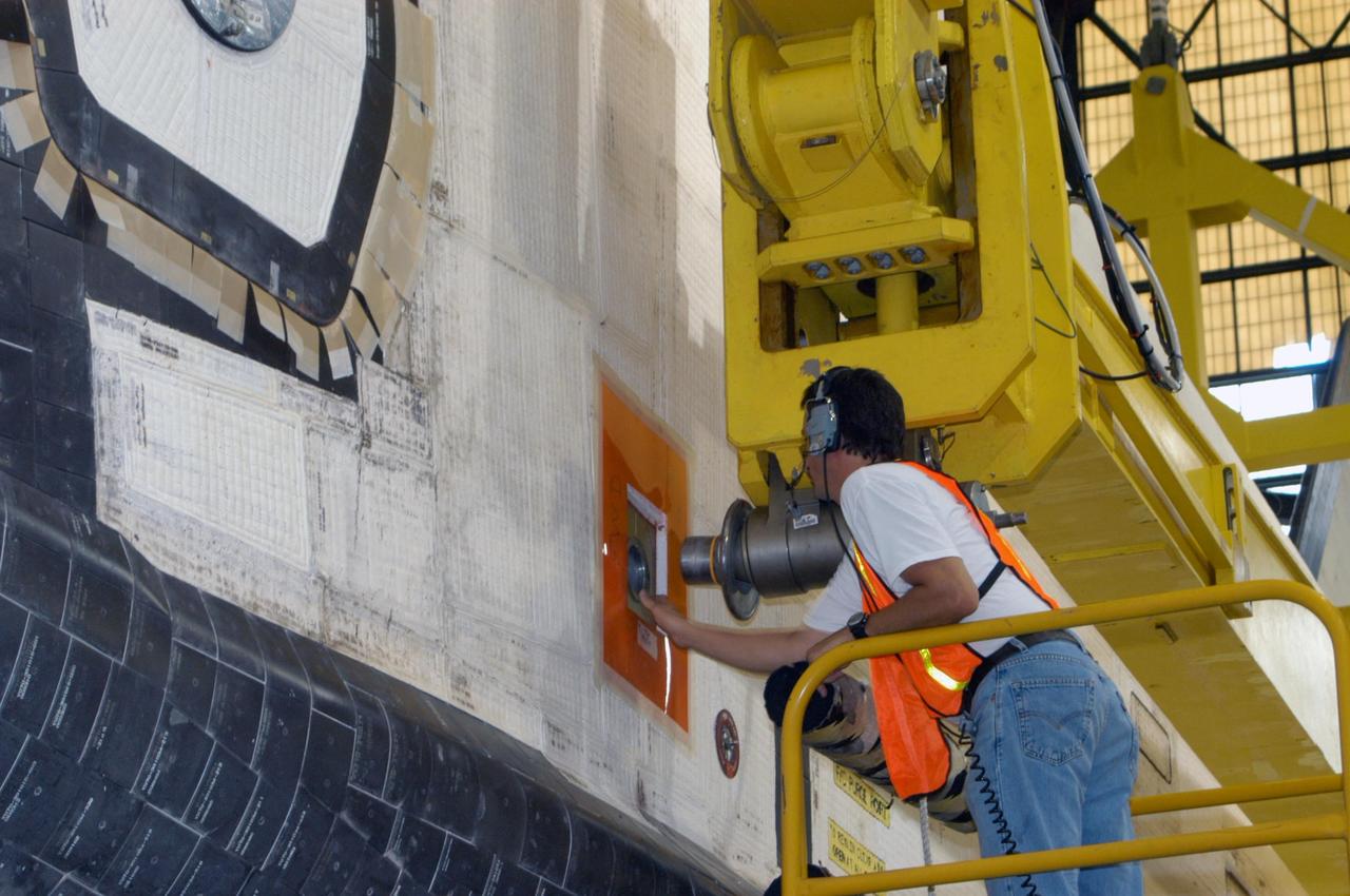 KENNEDY SPACE CENTER, FLA.  -    In the transfer aisle of the Vehicle Assembly Building, workers are securing the sling attachment of the overhead crane that will lift the orbiter Atlantis into high bay 3. After Atlantis is lifted and moved into the high bay, the orbiter will be lowered and mated with the external tank and solid rocket boosters already stacked on the mobile launcher platform.  Atlantis' launch window begins Aug. 28. During its 11-day mission to the International Space Station, the STS-115 crew of six astronauts will install the Port 3/4 truss segment with its two large solar arrays.   Photo credit: NASA/George Shelton