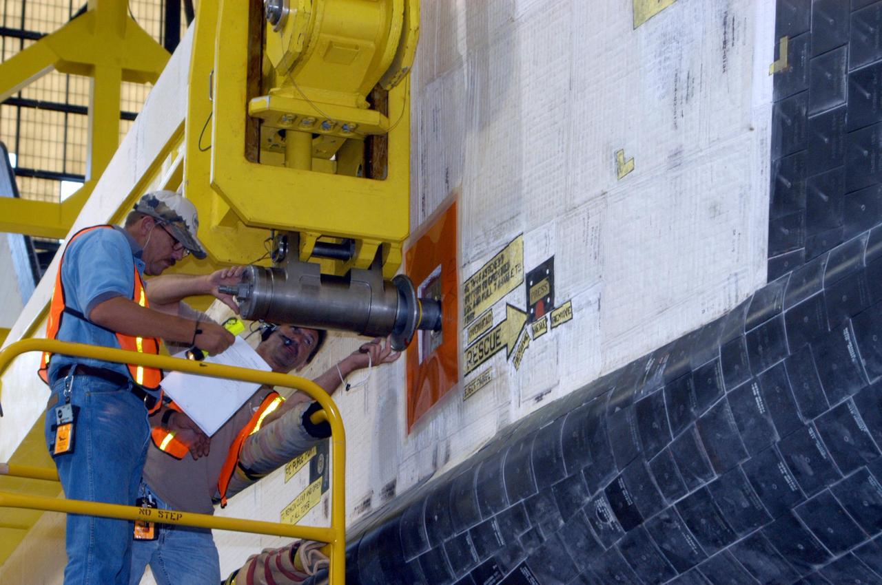 KENNEDY SPACE CENTER, FLA.  -    In the transfer aisle of the Vehicle Assembly Building, workers are securing the sling attachment of the overhead crane that will lift the orbiter Atlantis into high bay 3. After Atlantis is lifted and moved into the high bay, the orbiter will be lowered and mated with the external tank and solid rocket boosters already stacked on the mobile launcher platform.  Atlantis' launch window begins Aug. 28. During its 11-day mission to the International Space Station, the STS-115 crew of six astronauts will install the Port 3/4 truss segment with its two large solar arrays.   Photo credit: NASA/George Shelton