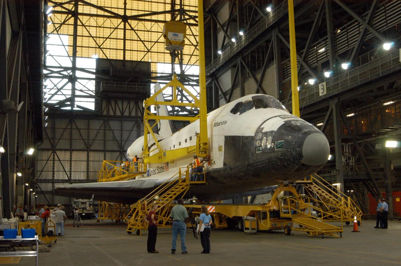 KENNEDY SPACE CENTER, FLA.  -    In the transfer aisle of the Vehicle Assembly Building, workers are securing the sling attachment of the overhead crane that will lift the orbiter Atlantis into high bay 3. After Atlantis is lifted and moved into the high bay, the orbiter will be lowered and mated with the external tank and solid rocket boosters already stacked on the mobile launcher platform.  Atlantis' launch window begins Aug. 28. During its 11-day mission to the International Space Station, the STS-115 crew of six astronauts will install the Port 3/4 truss segment with its two large solar arrays.   Photo credit: NASA/George Shelton