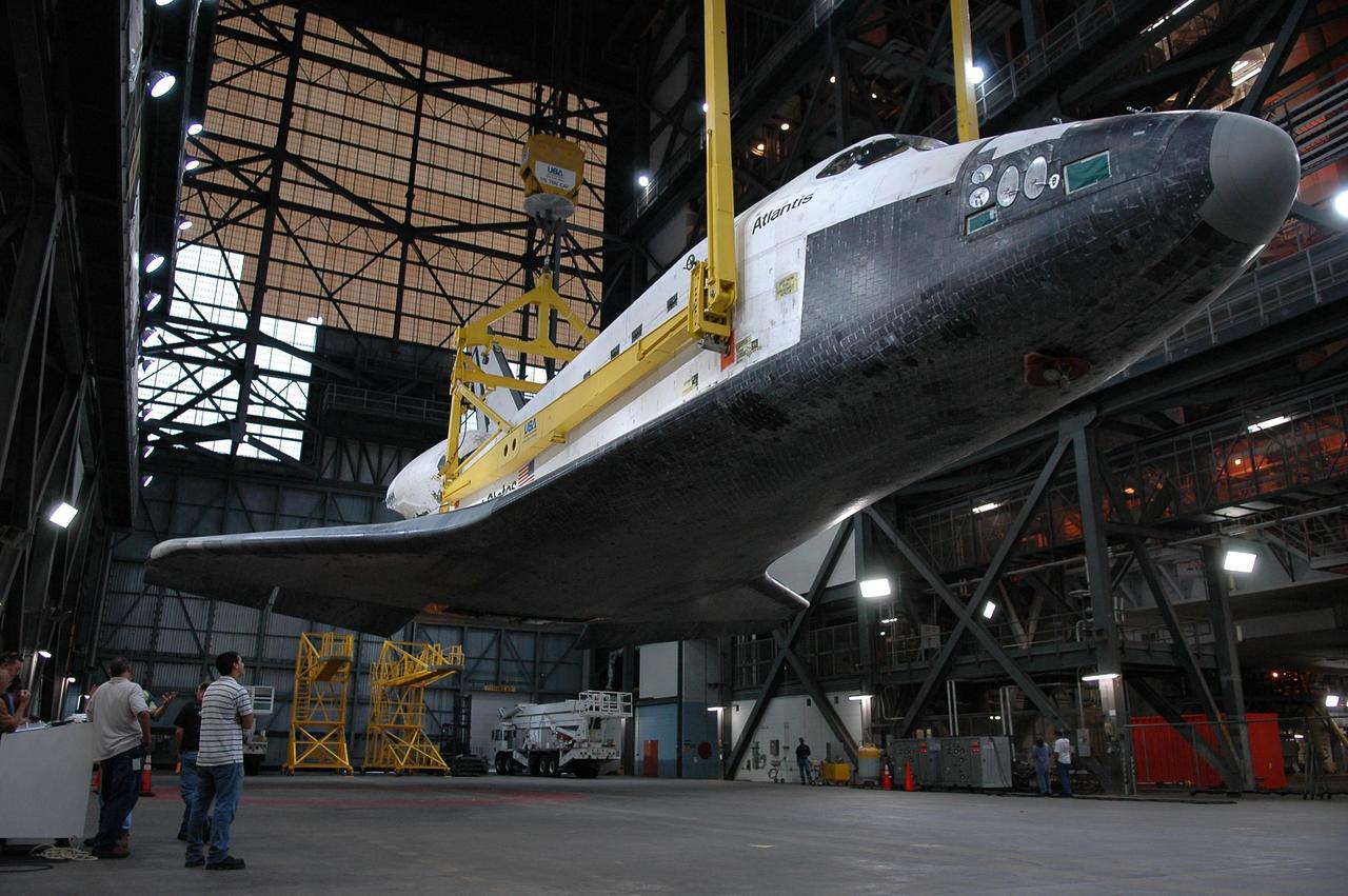 KENNEDY SPACE CENTER, FLA. - In the transfer aisle of the Vehicle Assembly Building, Atlantis seems to float above the floor as it is suspended by an overhead crane and sling. The orbiter will be raised to a vertical position and then will be lifted into high bay 3 for stacking with the external tank and solid rocket boosters already installed on the mobile launcher platform. After mating with the external tank and boosters, Atlantis will undergo a shuttle interface test and other prelaunch processing. Atlantis' launch window begins Aug. 28. During its 11-day mission to the International Space Station, the STS-115 crew of six astronauts will continue construction of the station and install their cargo, the Port 3/4 truss segment with its two large solar arrays. Photo credit: NASA/Kim Shiflett