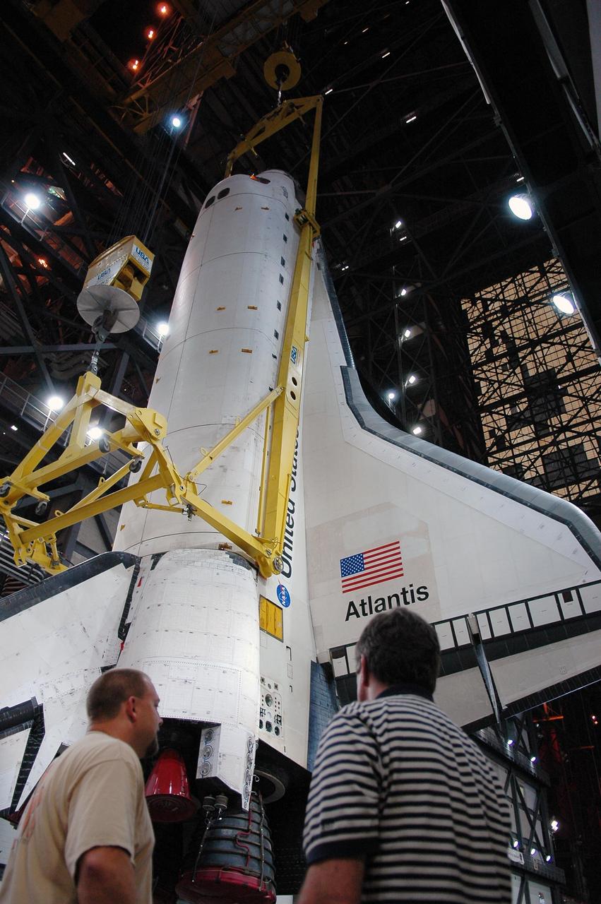 KENNEDY SPACE CENTER, FLA.  - In the transfer aisle of the Vehicle Assembly Building, an overhead crane and sling is ready to lift Atlantis into high bay 3 for stacking with the external tank and solid rocket boosters already installed on the mobile launcher platform.  After mating with the external tank and boosters, Atlantis will undergo a shuttle interface test and other prelaunch processing.  Atlantis' launch window begins Aug. 28. During its 11-day mission to the International Space Station, the STS-115 crew of six astronauts will continue construction of the station and install their cargo, the Port 3/4 truss segment with its two large solar arrays.  Photo credit: NASA/Kim Shiflett