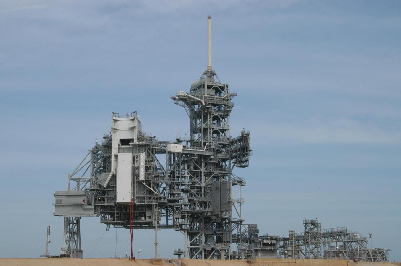 KENNEDY SPACE CENTER, FLA.  - On Launch Pad 39B, the payload canister is lifted toward the payload changeout room (PCR) for transfer of its cargo into the PCR.  The canister holds the payload for Atlantis and mission STS-115, the Port 3/4 truss segment with two large solar arrays. The red umbilical lines are still attached to the transporter, below it.  To the right of the rotating structure is the fixed service structure with the 80-foot lightning mast on top.  The payload changeout room provides an environmentally clean or "white room" condition in which to receive a payload transferred from a protective payload canister. After the shuttle arrives at the pad, the rotating service structure will close around it and the payload will then be transferred into Atlantis' payload bay.  Atlantis' launch window begins Aug. 28. During its 11-day mission to the International Space Station, the STS-115 crew of six astronauts will install  the truss, a 17-ton segment of the space station's truss backbone.  Photo credit: NASA/George Shelton