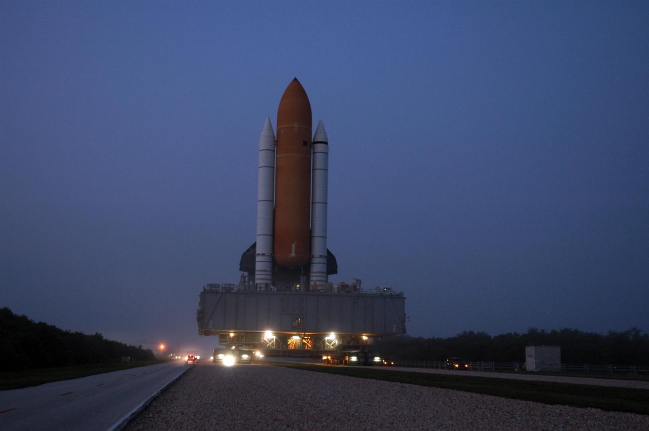 KENNEDY SPACE CENTER, FLA. - Looking like fireflies gathered around the behemoth mobile launcher platform and crawler-transporter, vehicles escort Space Shuttle Atlantis on its slow journey to Launch Pad 39B. First motion out of the Vehicle Assembly Building was 1:05 a.m. The slow speed of the crawler results in a 6-hour trek to the pad approximately 4 miles away. Atlantis' launch window begins Aug. 27 for an 11-day mission to the International Space Station. The STS-115 crew of six astronauts will continue construction of the station and install their cargo, the Port 3/4 truss segment with its two large solar arrays. Photo credit: NASA/Troy Cryder