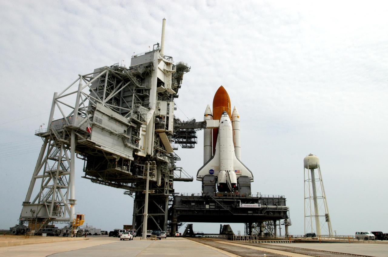 KENNEDY SPACE CENTER, FLA. - Space Shuttle Atlantis, atop the mobile launcher platform, sits on Launch Pad 39B after a nearly 8-hour crawl from the Vehicle Assembly Building. At left is the open rotating service structure and fixed service structure with the 80-foot lightning mast on top. Extended from the fixed structure is the orbiter access arm, with the White Room adjacent to Atlantis. At right is the 290-foot high, 300,000- gallon water tank that aids in sound suppression during launch. The water releases just prior to the ignition of the shuttle engines and flows through 7-foot-diameter pipes for about 20 seconds, pouring into 16 nozzles atop the flame deflectors and from outlets in the main engines exhaust hole in the mobile launcher platform. Atlantis' launch window begins Aug. 27 for an 11-day mission to the International Space Station. The STS-115 crew of six astronauts will continue construction of the station and install their cargo, the Port 3/4 truss segment with its two large solar arrays. Photo credit: NASA/Troy Cryder & George Shelton