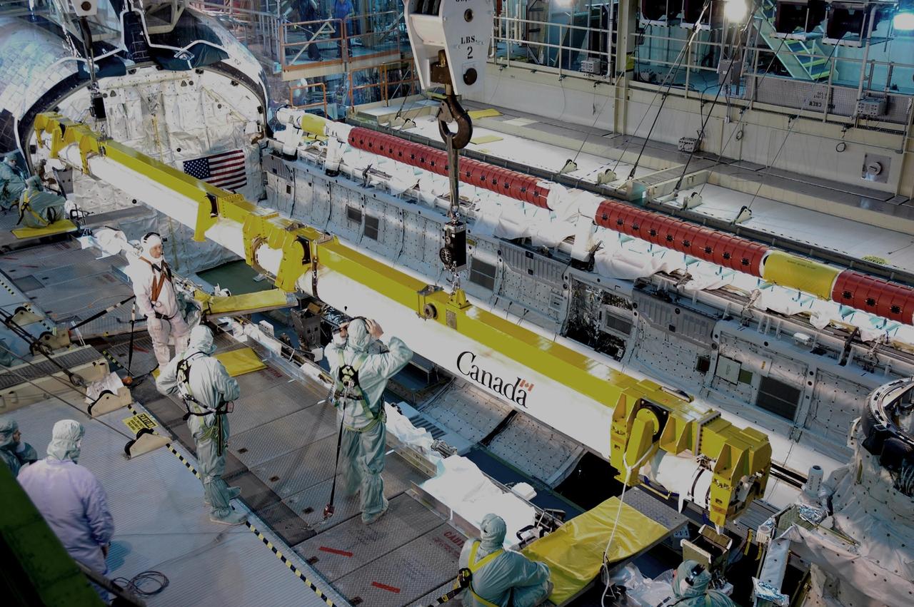 KENNEDY SPACE CENTER, FLA. -  Suspended by cables in bay 3 of the Orbiter Processing Facility, the orbiter boom sensor system is lowered toward its place in Discovery's payload bay.   It was removed last week in order to inspect the power system, which is routine after every flight.  Discovery returned from mission STS-121 in late July, and is now being processed for mission STS-116, scheduled to launch in mid-December. Photo credit: NASA/Jim Grossmann