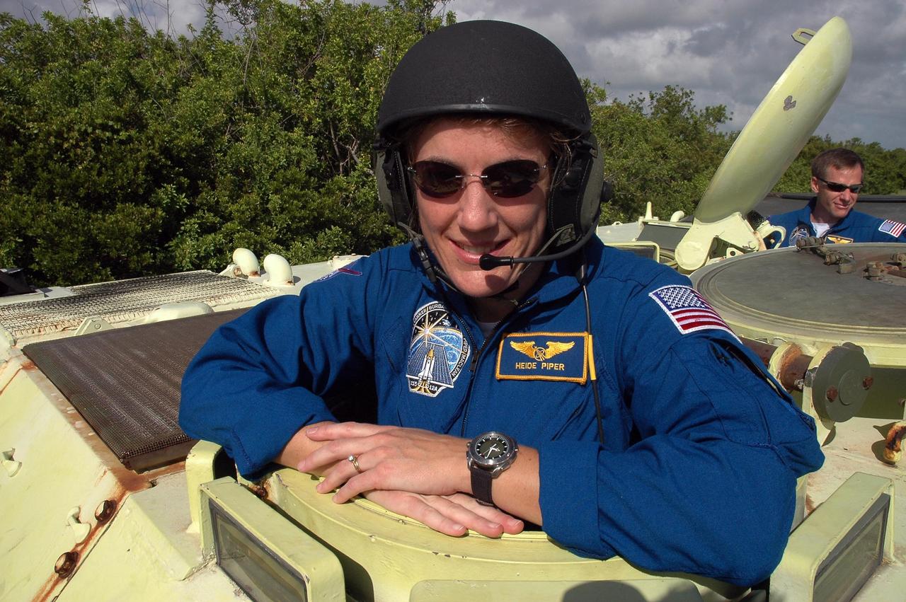 KENNEDY SPACE CENTER, FLA. -  STS-115 Mission Specialist Heidemarie Stefanyshyn-Piper is ready to practice driving the M-113 armored personnel carrier.  Behind her is pilot Christopher Ferguson. The STS-115 crew are at NASA's Kennedy Space Center for Terminal Countdown Demonstration Test activities such as the M-113 training.  They will also practice emergency egress from the launch pad and take part in a simulated launch countdown.  Liftoff of mission STS-115 aboard Space Shuttle Atlantis is scheduled in a window beginning Aug. 27.   Photo credit: NASA/Cory Huston
