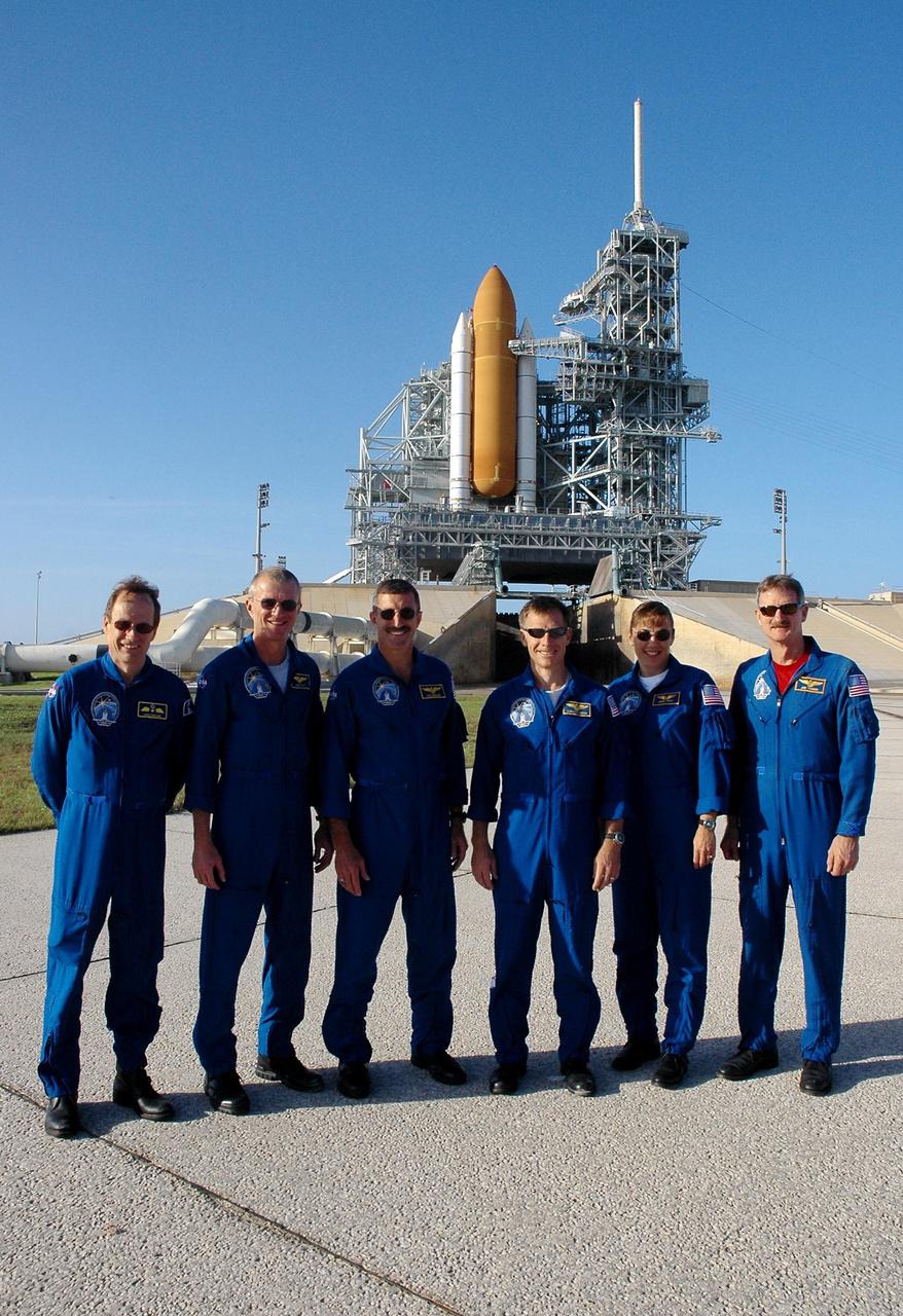KENNEDY SPACE CENTER, FLA. - The STS-115 crew poses for the media before a press conference on Launch Pad 39B. Seen left to right are Mission Specialist Steven MacLean, Commander Brent Jett, Mission Specialist Daniel Burbank, Pilot Chris Ferguson, and Mission Specialists Heidemarie Stefanyshyn-Piper and Joseph Tanner. MacLean is with the Canadian Space Agency. The mission crew is at KSC for Terminal Countdown Demonstration Test activities that are preparation for launch on Space Shuttle Atlantis, scheduled to take place in a window that opens Aug. 27. Behind the crew is the shuttle, surrounded by the fixed and rotating service structures, with the orange external tank and while solid rocket boosters showing. The TCDT culminates in a simulated launch countdown. During their 11-day mission to the International Space Station, the STS-115 crew will continue construction of the station and attach the payload elements, the Port 3/4 truss segment with its two large solar arrays. Photo credit: NASA/Cory Huston