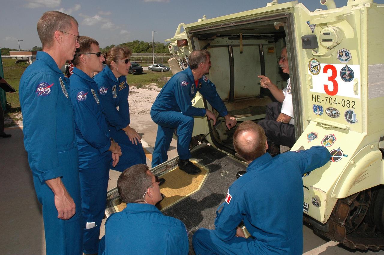 KENNEDY SPACE CENTER, FLA. - STS-115 crew members take another look at an M-113 armored personnel carrier that could be used to move quickly away from the launch pad in the event of an emergency. From left are Commander Brent Jett, Pilot Chris Ferguson and Mission Specialists Heidemarie Stefanyshyn-Piper and Joseph Tanner. In the foreground are Mission Specialists Daniel Burbank and Steven MacLean, who is with the Canadian Space Agency. The mission crew is at KSC for Terminal Countdown Demonstration Test (TCDT) activities that are preparation for launch on Space Shuttle Atlantis, scheduled to take place in a window that opens Aug. 27. During their 11-day mission to the International Space Station, the STS-115 crew will continue construction of the station and attach the payload elements, the Port 3/4 truss segment with its two large solar arrays. Photo credit: NASA/Cory Huston