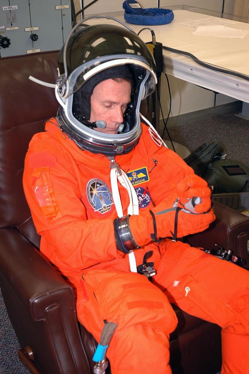 KENNEDY SPACE CENTER, FLA. - The STS-115 crew members are suiting up for their simulated launch countdown. Shown here fixing his glove is Mission Specialist Steven MacLean, who is with the Canadian Space Agency. The mission crew is at KSC for Terminal Countdown Demonstration Test (TCDT) activities that are preparation for launch on Space Shuttle Atlantis, scheduled to take place in a window that opens Aug. 27. The TCDT has included emergency egress training as well as the simulation. During their 11-day mission to the International Space Station, the STS-115 crew will continue construction of the station and attach the payload elements, the Port 3/4 truss segment with its two large solar arrays. Photo credit: NASA/Cory Huston