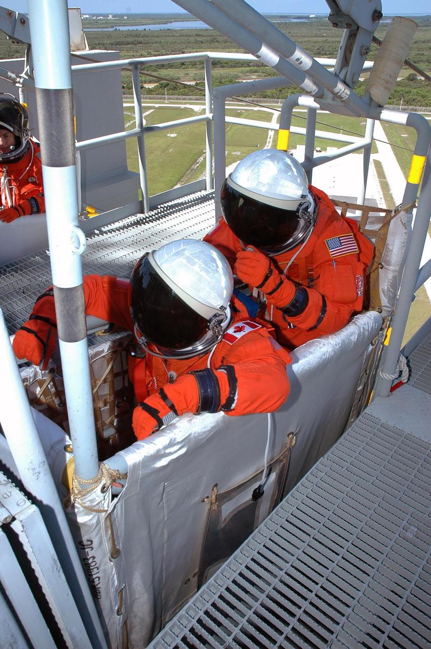 KENNEDY SPACE CENTER, FLA. - STS-115 Mission Specialists Steven MacLean (left) and Joseph Tanner are ready to release the slidewire basket on Launch Pad 39B, practicing emergency egress procedures. The activity follows a simulated launch countdown, part of Terminal Countdown Demonstration Test activities. The TCDT is a prelaunch preparation for the mission that is scheduled to lift off in a window opening Aug. 27. During their 11-day mission to the International Space Station, the STS-115 crew will continue construction of the station and attach the payload elements, the Port 3/4 truss segment with its two large solar arrays. Photo credit: NASA/Cory Huston