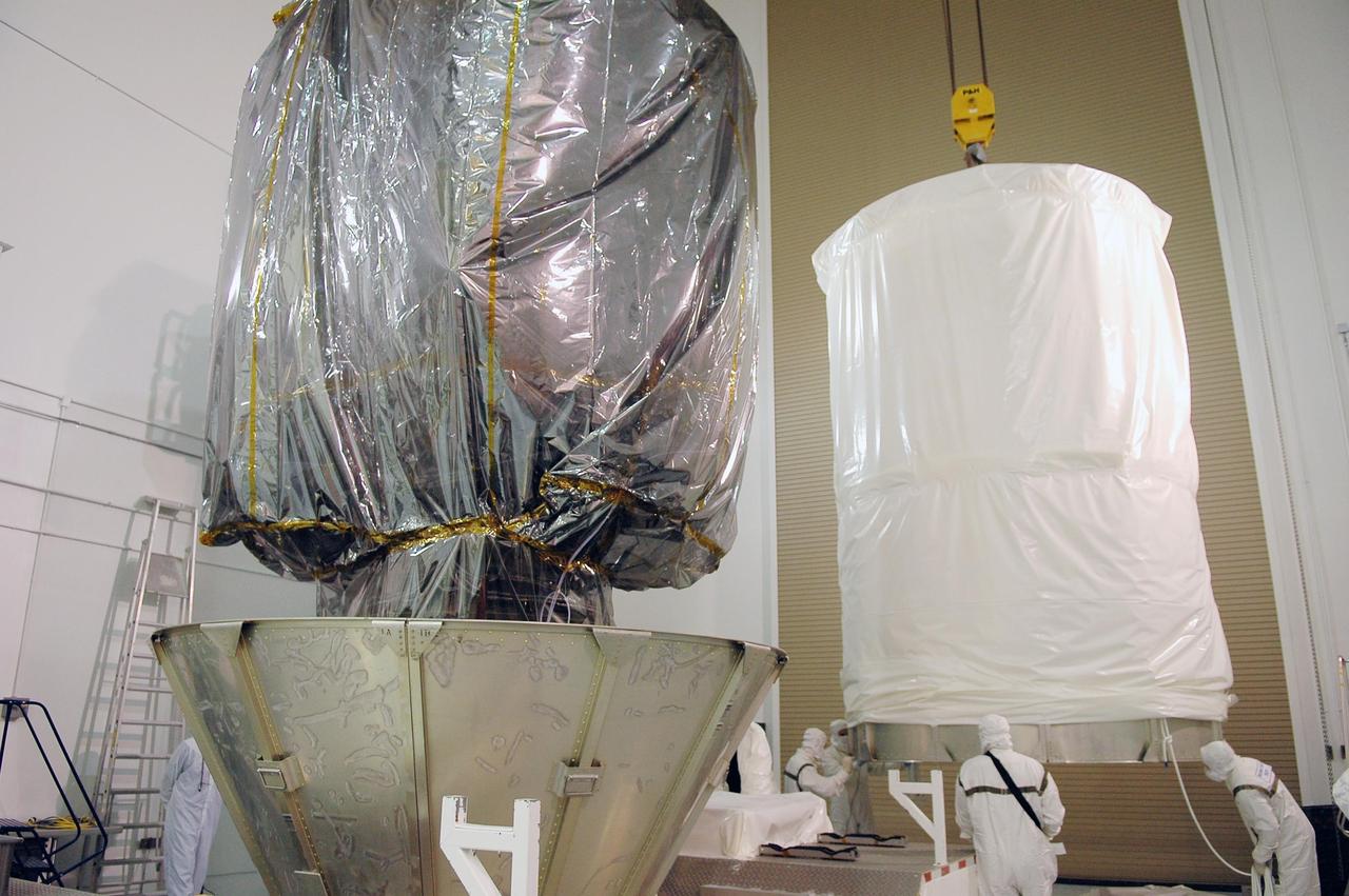 KENNEDY SPACE CENTER, FLA. - At Astrotech Space Operations in Titusville, Fla., workers maneuver the upper portion of the transportation canister that will be lowered over the STEREO spacecraft (in front). When the entire configuration is encased, it will be moved to Launch Pad 17-B at Cape Canaveral Air Force Station. STEREO stands for Solar Terrestrial Relations Observatory and comprises two spacecraft. The STEREO mission is the first to take measurements of the sun and solar wind in 3-dimension. This new view will improve our understanding of space weather and its impact on the Earth. STEREO is expected to lift off Aug. 31. Photo credit: NASA/Kim Shiflett