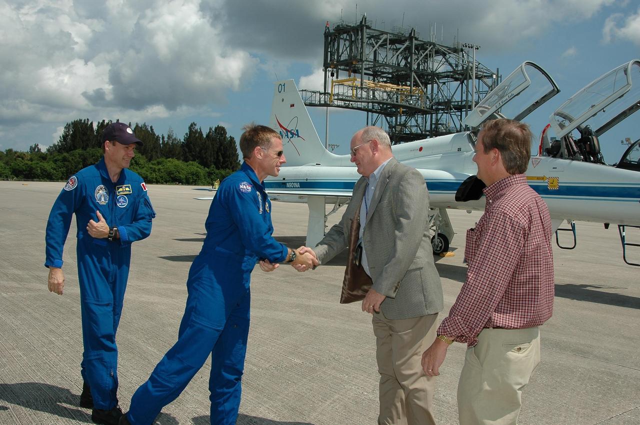 KENNEDY SPACE CENTER, FLA. -  The crew of mission STS-115 arrives at NASA Kennedy Space Center's Shuttle Landing Facility to prepare for launch on Aug. 27 to the International Space Station.  Seen here are (left to right) Mission Specialist Steven MacLean and Pilot Christopher Ferguson being greeted by KSC Associate Director Jim Hattaway and Shuttle Launch Director Mike Leinbach. The mission will deliver and install the 17-and-a-half-ton P3/P4 truss segment to the port side of the integrated truss system on the orbital outpost.  The truss includes a new set of photovoltaic solar arrays.  When unfurled to their full length of 240 feet, the arrays will provide additional power for the station in preparation for the delivery of international science modules over the next two years.  STS-115 is expected to last 11 days and includes three scheduled spacewalks.    Photo credit: NASA/Kim Shiflett