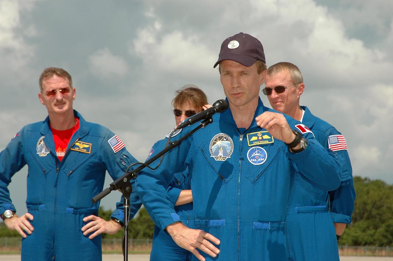 KENNEDY SPACE CENTER, FLA. - The crew of mission STS-115 stop to talk to the media after arriving at NASA Kennedy Space Center's Shuttle Landing Facility to prepare for launch on Aug. 27 to the International Space Station. Seen here, left to right, are Mission Specialists Joseph Tanner, Heidemarie Stefanyshyn-Piper and Steven MacLean (at the microphone), and Commander Brent Jett. The mission will deliver and install the 17-and-a-half-ton P3/P4 truss segment to the port side of the integrated truss system on the orbital outpost. The truss includes a new set of photovoltaic solar arrays. When unfurled to their full length of 240 feet, the arrays will provide additional power for the station in preparation for the delivery of international science modules over the next two years. STS-115 is expected to last 11 days and includes three scheduled spacewalks. Photo credit: NASA/Kim Shiflett