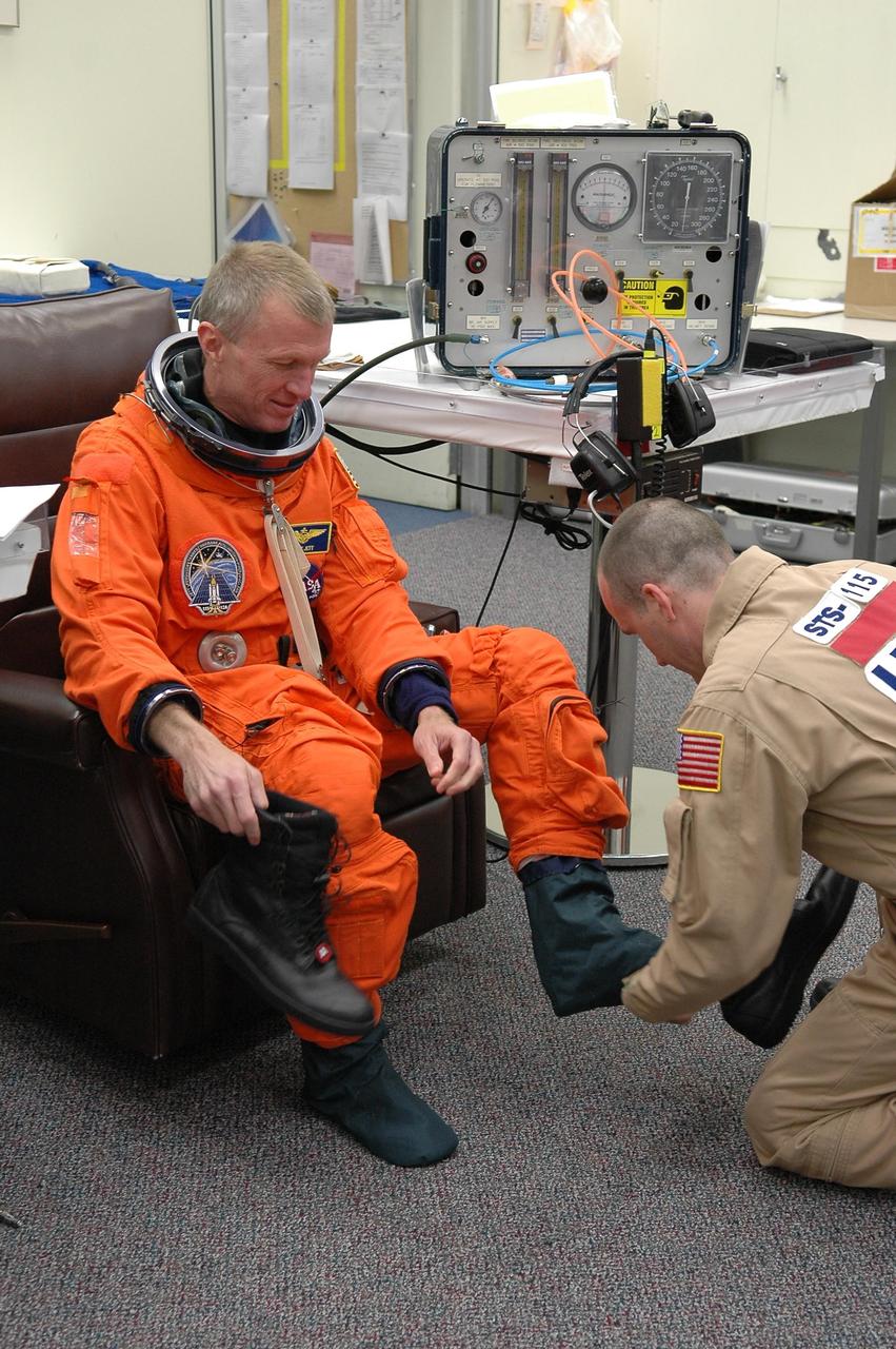 KENNEDY SPACE CENTER, FLA. -    STS-115 Commander Brent Jett is helped donning his launch suit before flying the Shuttle Training Aircraft to practice landing the shuttle.  STA practice is part of launch preparations.   The STA is a Grumman American Aviation-built Gulf Stream II jet that was modified to simulate an orbiter’s cockpit, motion and visual cues, and handling qualities. In flight, the STA duplicates the orbiter’s atmospheric descent trajectory from approximately 35,000 feet altitude to landing on a runway. Because the orbiter is unpowered during re-entry and landing, its high-speed glide must be perfectly executed the first time.  Mission STS-115 is scheduled to lift off about 4:30 p.m. Aug. 27.  The crew will deliver and install the P3/P4 segment to the port side of the integrated truss system on the International Space Station.  The truss includes a new set of photovoltaic solar arrays.  When unfurled to their full length of 240 feet, the arrays will provide additional power for the station in preparation for the delivery of international science modules over the next two years.  The mission is expected to last 11 days and includes three scheduled spacewalks.   Photo credit: NASA/Kim Shiflett