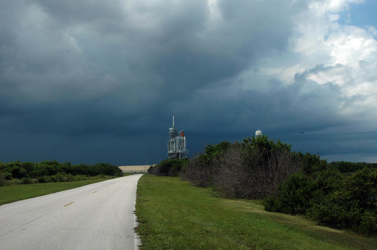 KENNEDY SPACE CENTER, FLA. -  The dark clouds of a heavy rainstorm moving into Kennedy Space Center in the late afternoon on Sat., August 26, 2006, seem to illuminate the Space Shuttle Atlantis as it sits on Launch Pad 39B. A lightning strike to the pad's lightning protection system on August 25, caused the mission management team to postpone the launch of mission STS-115 for 24 hours in order to review all electrical systems on the space shuttle and ground support equipment at the pad. Photo credit: NASA/Ken Thornsley.