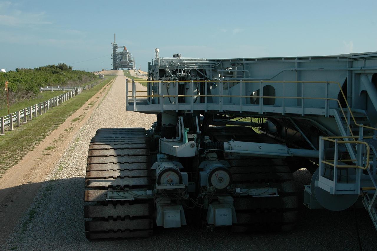 KENNEDY SPACE CENTER, FLA. -   Crawler-transporter No. 2 makes its way toward Launch Pad 39B (in the background).  The tip of the orange external tank can be seen above the rotating service structure surrounding the shuttle.  The crawler is being moved nearby in the event the mission management team decides to roll back Space Shuttle Atlantis due to Hurricane Ernesto.  The hurricane has been forecast on a heading north and east from Cuba, taking it along the eastern coast of Florida.   NASA's lighted launch window extends to Sept. 13, but mission managers are hoping to launch on mission STS-115 by Sept. 7 to avoid a conflict with a Russian Soyuz rocket also bound for the International Space Station. The crawler is 131 feet long, 113 feet wide and 20 feet high.  It weights 5.5 million pounds unloaded.  The combined weight of crawler, mobile launcher platform and a space shuttle is 12 million pounds. Unloaded, the crawler moves at 2 mph.  Loaded, the snail's pace slows to 1 mph.    Photo credit: NASA/Kim Shiflett