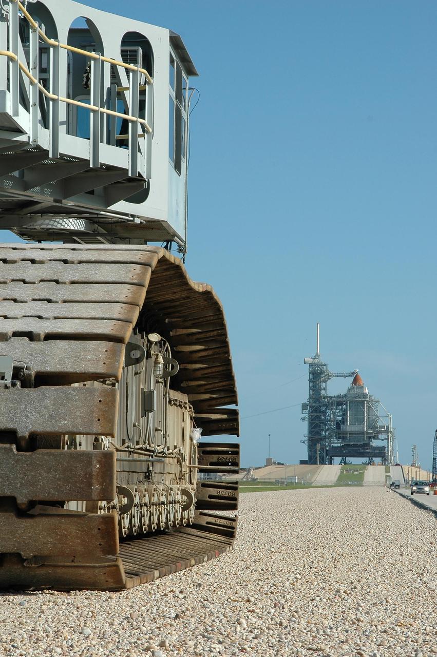KENNEDY SPACE CENTER, FLA. -   Crawler-transporter No. 2 nears Launch Pad 39B (in the background, right).  The tip of the orange external tank can be seen above the rotating service structure surrounding the shuttle.  The crawler is being moved nearby in the event the mission management team decides to roll back Space Shuttle Atlantis due to Hurricane Ernesto.  The hurricane has been forecast on a heading north and east from Cuba, taking it along the eastern coast of Florida.   NASA's lighted launch window extends to Sept. 13, but mission managers are hoping to launch on mission STS-115 by Sept. 7 to avoid a conflict with a Russian Soyuz rocket also bound for the International Space Station. The crawler is 131 feet long, 113 feet wide and 20 feet high.  It weights 5.5 million pounds unloaded.  The combined weight of crawler, mobile launcher platform and a space shuttle is 12 million pounds. Unloaded, the crawler moves at 2 mph.  Loaded, the snail's pace slows to 1 mph.    Photo credit: NASA/Kim Shiflett