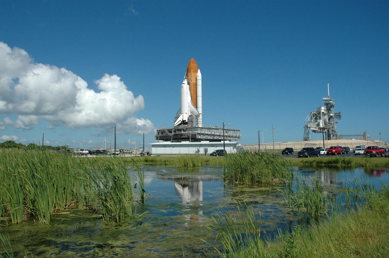 KENNEDY SPACE CENTER, FLA. - Reeds muddle the reflection of Space Shuttle Atlantis in the pond next to Launch Pad 39B. The shuttle is rolling back to the Vehicle Assembly Building. First motion off the pad was at 10:04 a.m. EDT. The rollback is a safety precaution as the area waits for the arrival of Tropical Storm Ernesto. The storm is forecast to be bringing 58-mph to 70-mph winds in the next 24 hours. The shuttle will be moved into high bay 2, on the southwest side of the VAB, for protection from the storm. Photo credit: NASA/Jack Pfaller