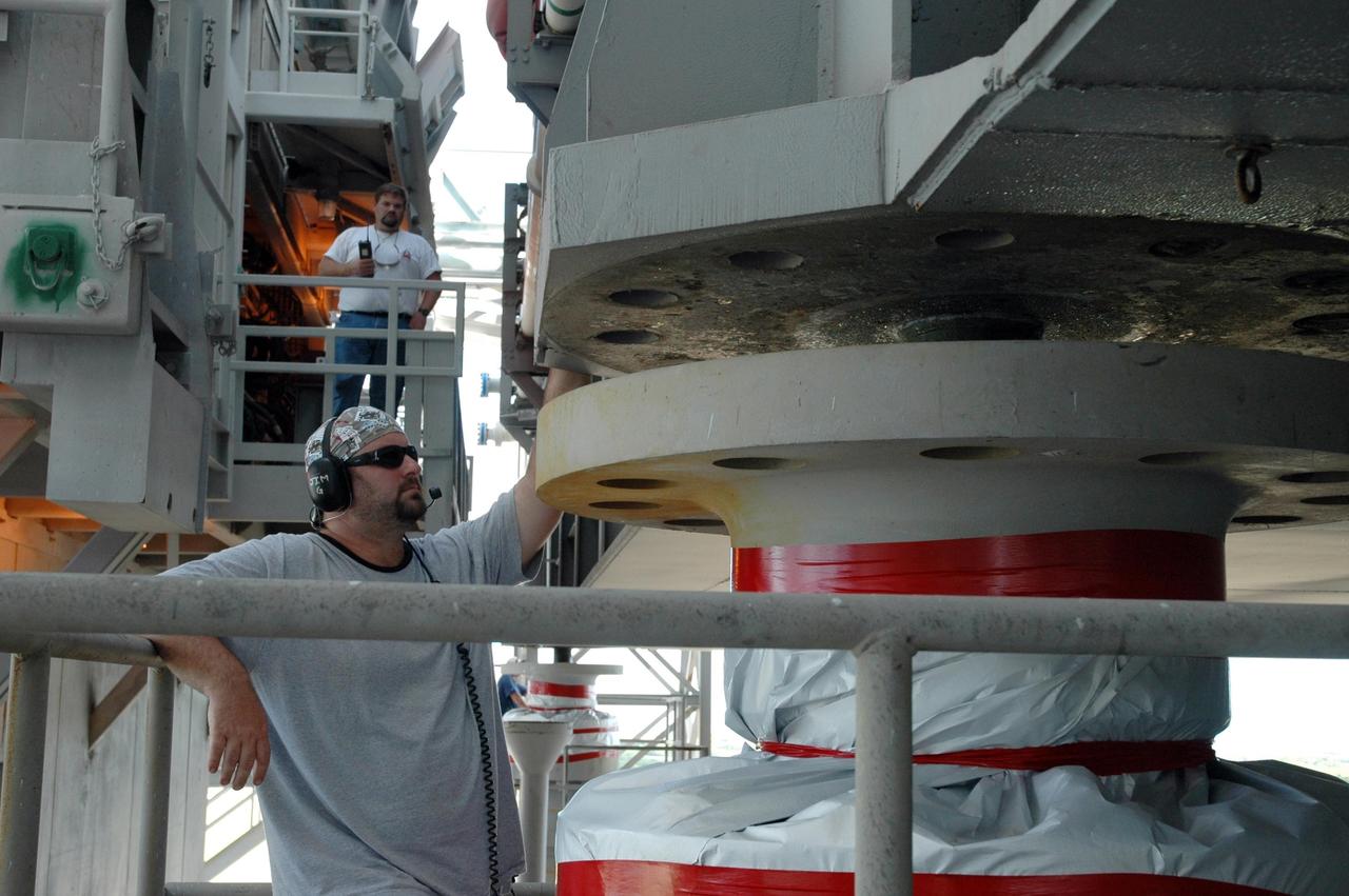 KENNEDY SPACE CENTER, FLA. - On Launch Pad 39B, a worker checks the progress of one of the corner bolts of the crawler-transporter that support the mobile launcher platform during transport. Space Shuttle Atlantis, which sits on top of the mobile launcher platform, will be rolled back to the Vehicle Assembly Building. First motion off the pad was at 10:04 a.m. EDT. The rollback is a safety precaution as the area waits for the arrival of Tropical Storm Ernesto. The storm is forecast to be bringing 58-mph to 70-mph winds in the next 24 hours. The shuttle will be moved into high bay 2, on the southwest side of the VAB, for protection from the storm. Photo credit: NASA/Jack Pfaller