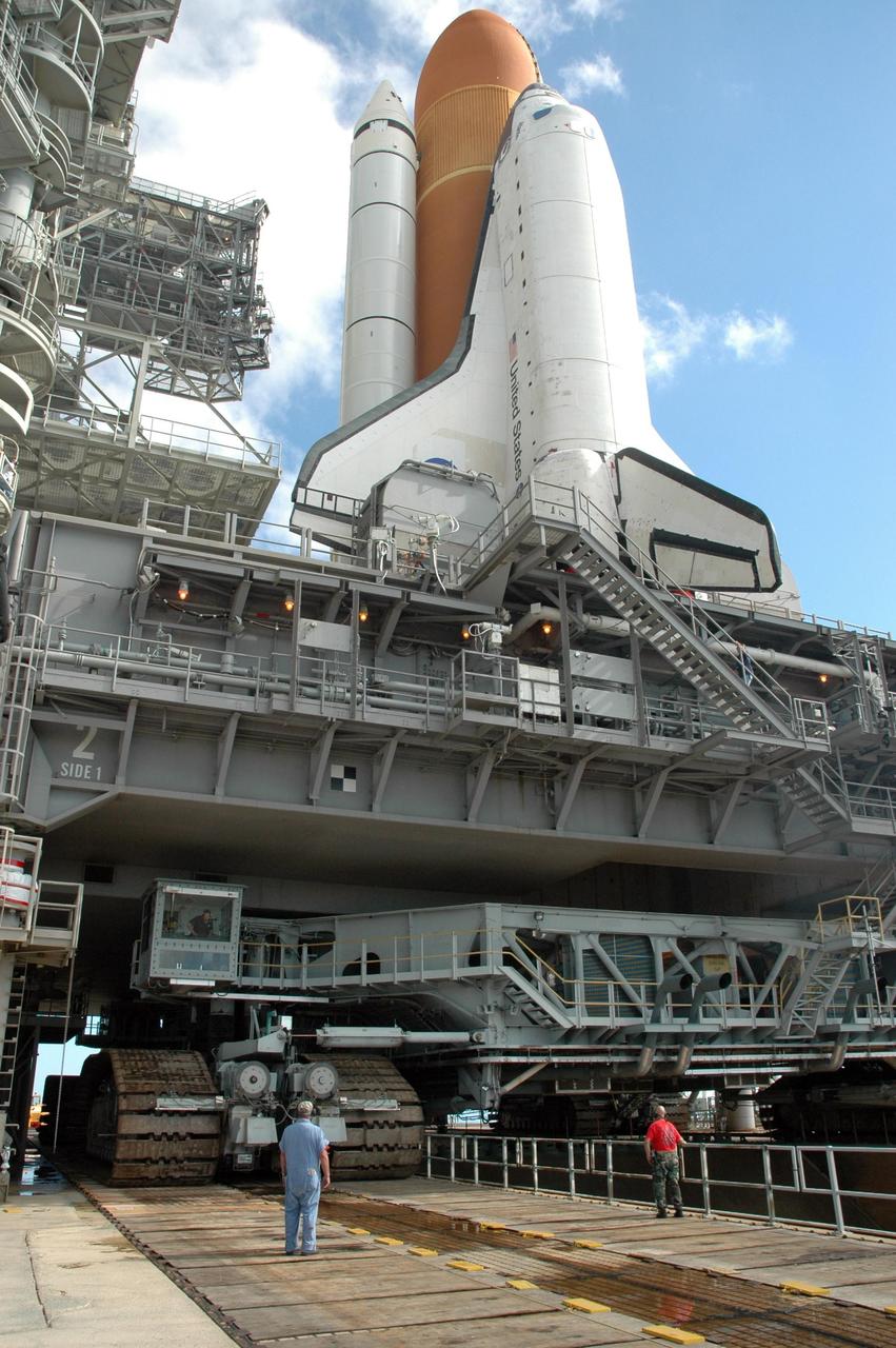 KENNEDY SPACE CENTER, FLA. - On Launch Pad 39B, the crawler-transporter (below) begins rolling away with its cargo above of the Space Shuttle Atlantis and mobile launcher platform. The shuttle is rolling back to the Vehicle Assembly Building. First motion off the pad was at 10:04 a.m. EDT. The rollback is a safety precaution as the area waits for the arrival of Tropical Storm Ernesto. The storm is forecast to be bringing 58-mph to 70-mph winds in the next 24 hours. The shuttle will be moved into high bay 2, on the southwest side of the VAB, for protection from the storm. Photo credit: NASA/Jack Pfaller