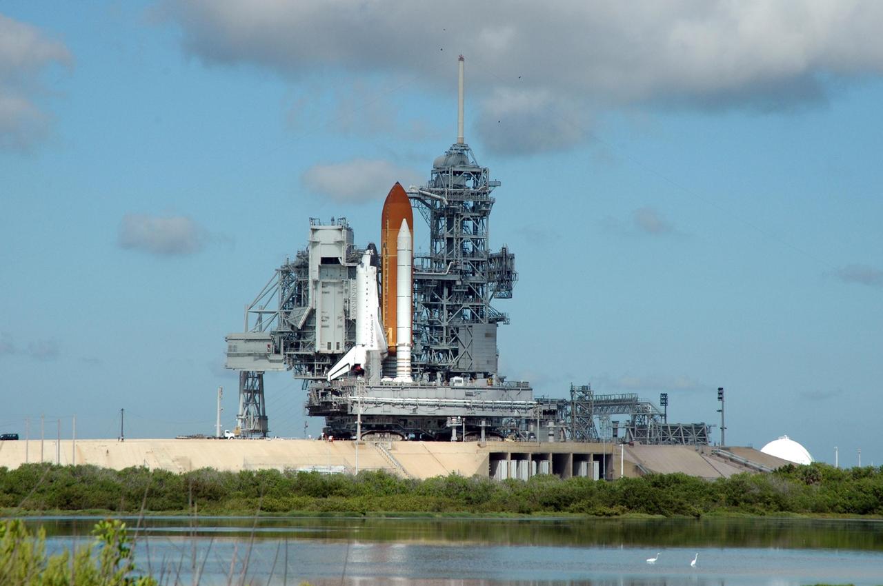 KENNEDY SPACE CENTER, FLA. -   A serene scene surrounds Space Shuttle Atlantis as it begins rolling off Launch Pad 39B to return to the Vehicle Assembly Building.  First motion off the pad was at 10:04 a.m. EDT.  The crawler is 131 feet long, 113 feet wide and 20 feet high. It weights 5.5 million pounds unloaded. The combined weight of crawler, mobile launcher platform and a space shuttle is 12 million pounds. Unloaded, the crawler moves at 2 mph. Loaded, the snail's pace slows to 1 mph. The rollback is a safety precaution as the area waits for the arrival of Tropical Storm Ernesto.  The storm is forecast to be bringing 58-mph to 70-mph winds in the next 24 hours.  The shuttle will be moved into high bay 2, on the southwest side of the VAB, for protection from the storm.  Photo credit: NASA/Ken Thornsley