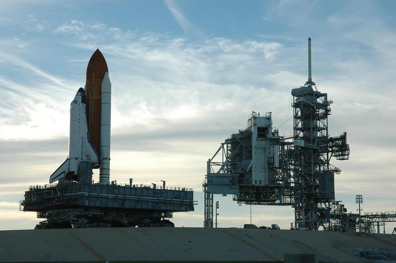 KENNEDY SPACE CENTER, FLA. - Space Shuttle Atlantis rolls up the ramp to Launch Pad 39B atop the crawler-transporter.   The crawler has a leveling system designed to keep the top of the space shuttle vertical while negotiating the 5-percent grade leading to the top of the launch pad. Also, a laser docking system provides almost pinpoint accuracy when the crawler and mobile launcher platform are positioned at the launch pad.  At right are the open rotating service structure and the fixed service structure topped by the 80-foot lightning mast. The shuttle had been moved off the launch pad due to concerns about the impact of Tropical Storm Ernesto, expected within 24 hours.  The forecast of lesser winds expected from Ernesto and its projected direction convinced Launch Integration Manager LeRoy Cain and Shuttle Launch Director Mike Leinbach to return the shuttle to the launch pad.   Photo credit: NASA/Kim Shiflett